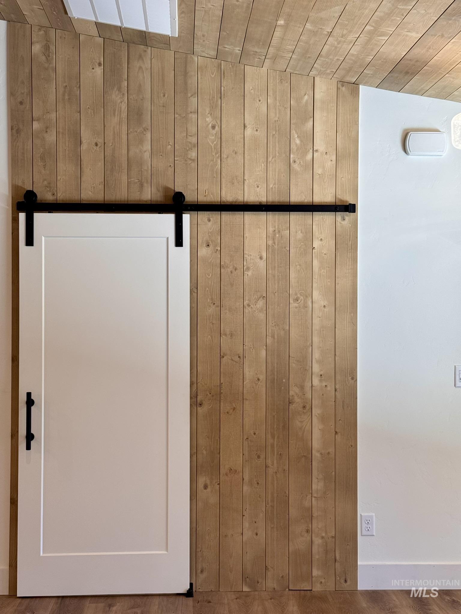 Detailed view of wooden walls, a barn door, wood finished floors, and wooden ceiling