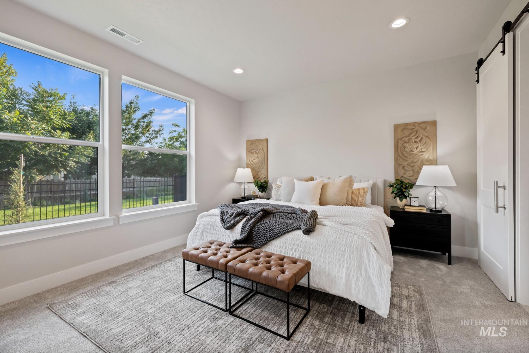 Bedroom featuring a barn door, light carpet, and recessed lighting