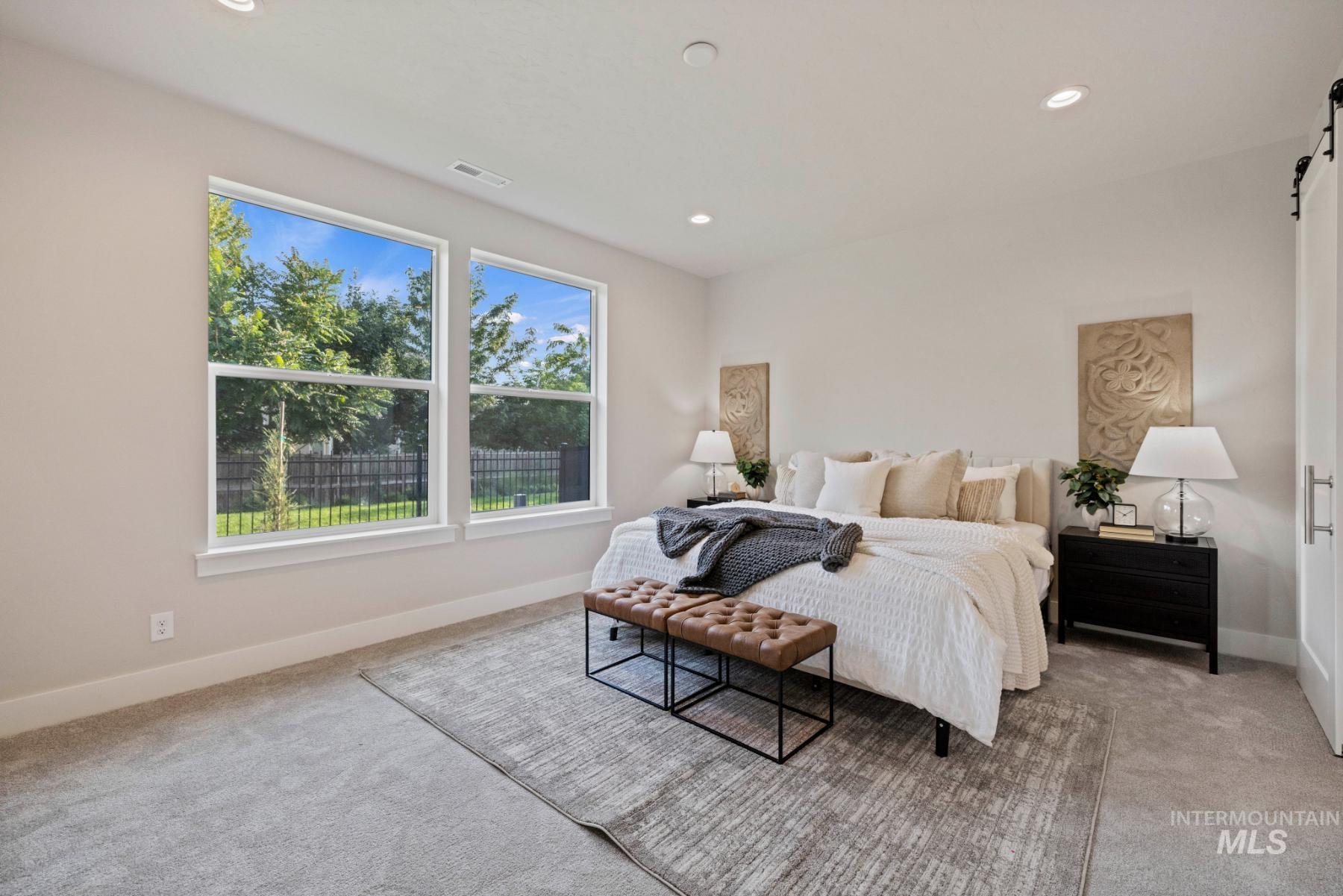 Bedroom featuring a barn door, light carpet, and recessed lighting
