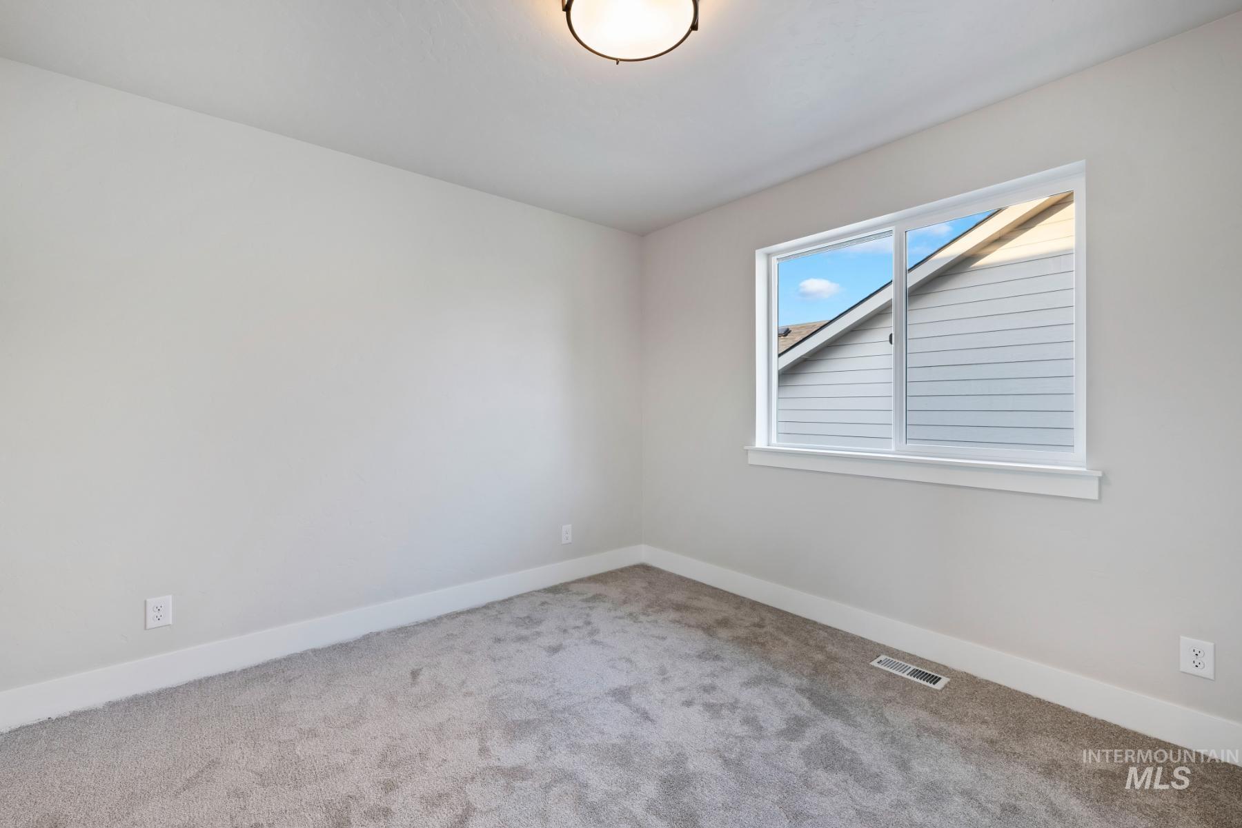 Carpeted spare room featuring baseboards