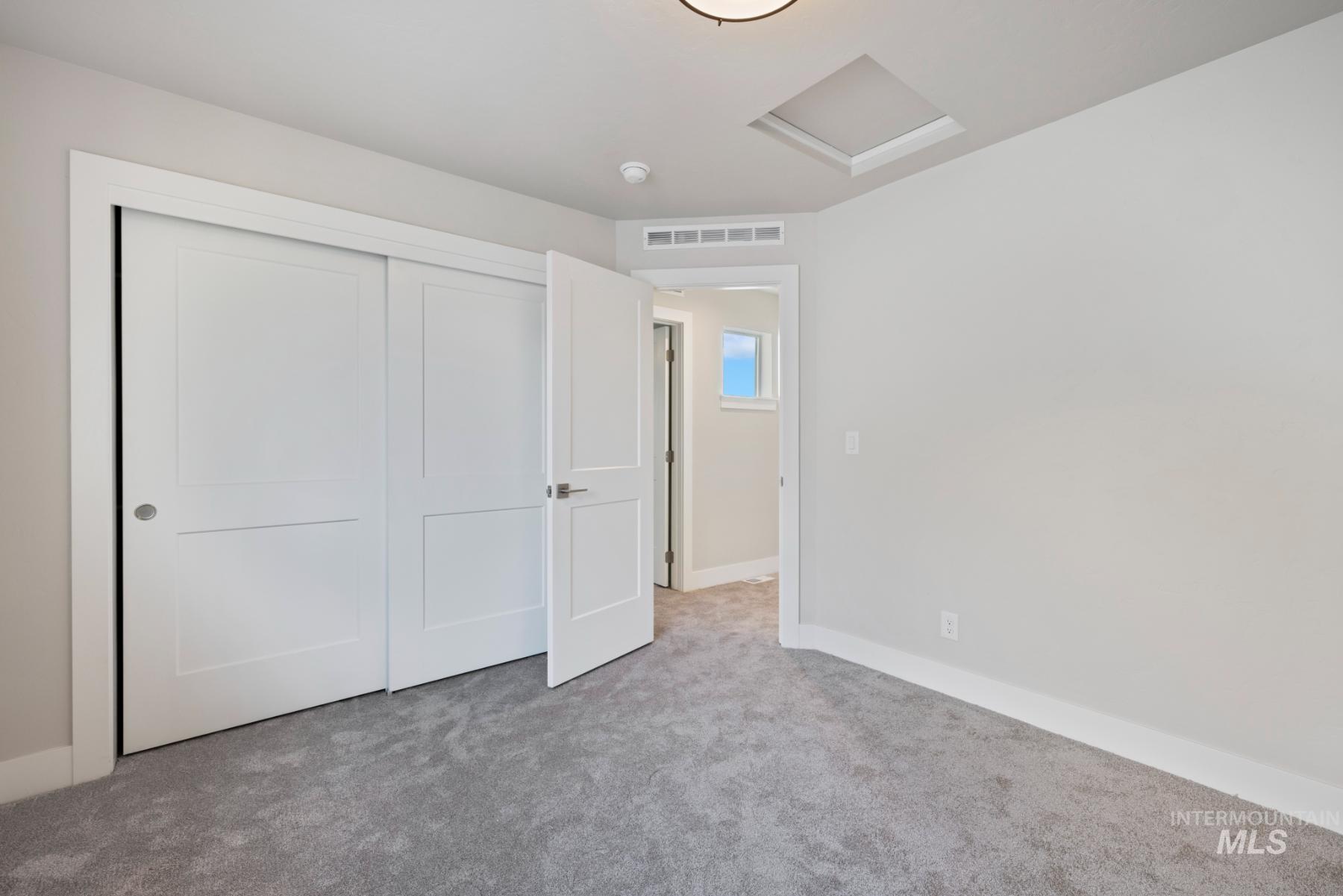 Unfurnished bedroom with attic access, carpet flooring, and a closet