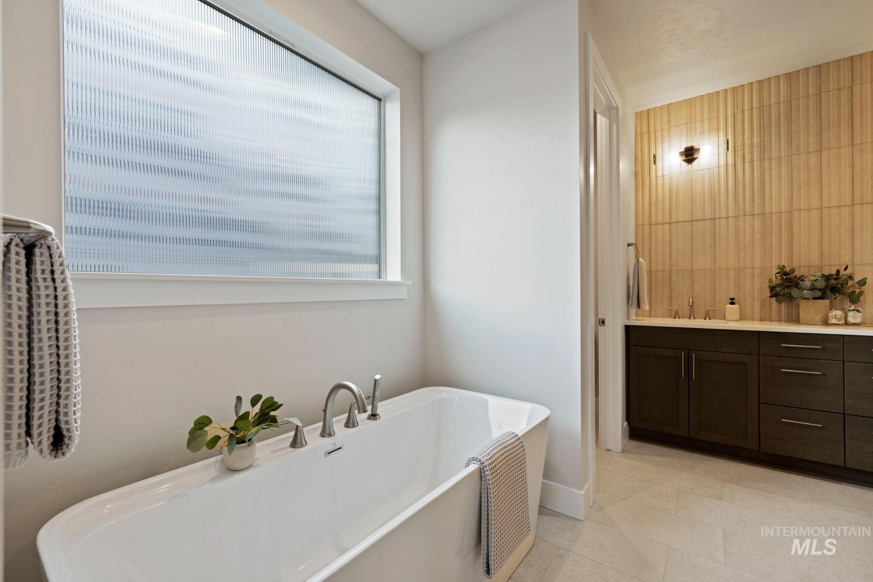Full bathroom featuring vanity, a soaking tub, and light tile patterned flooring