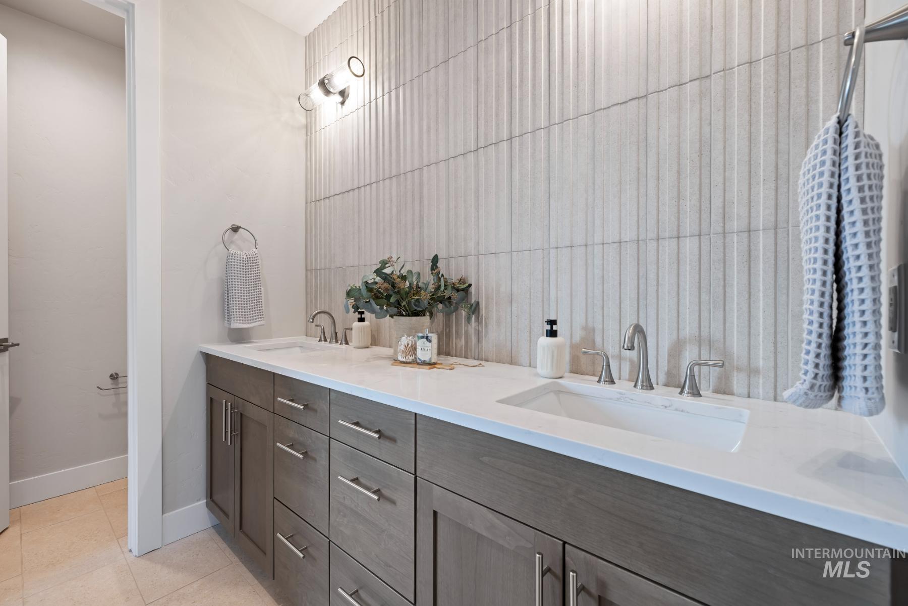 Bathroom with light tile patterned floors and double vanity