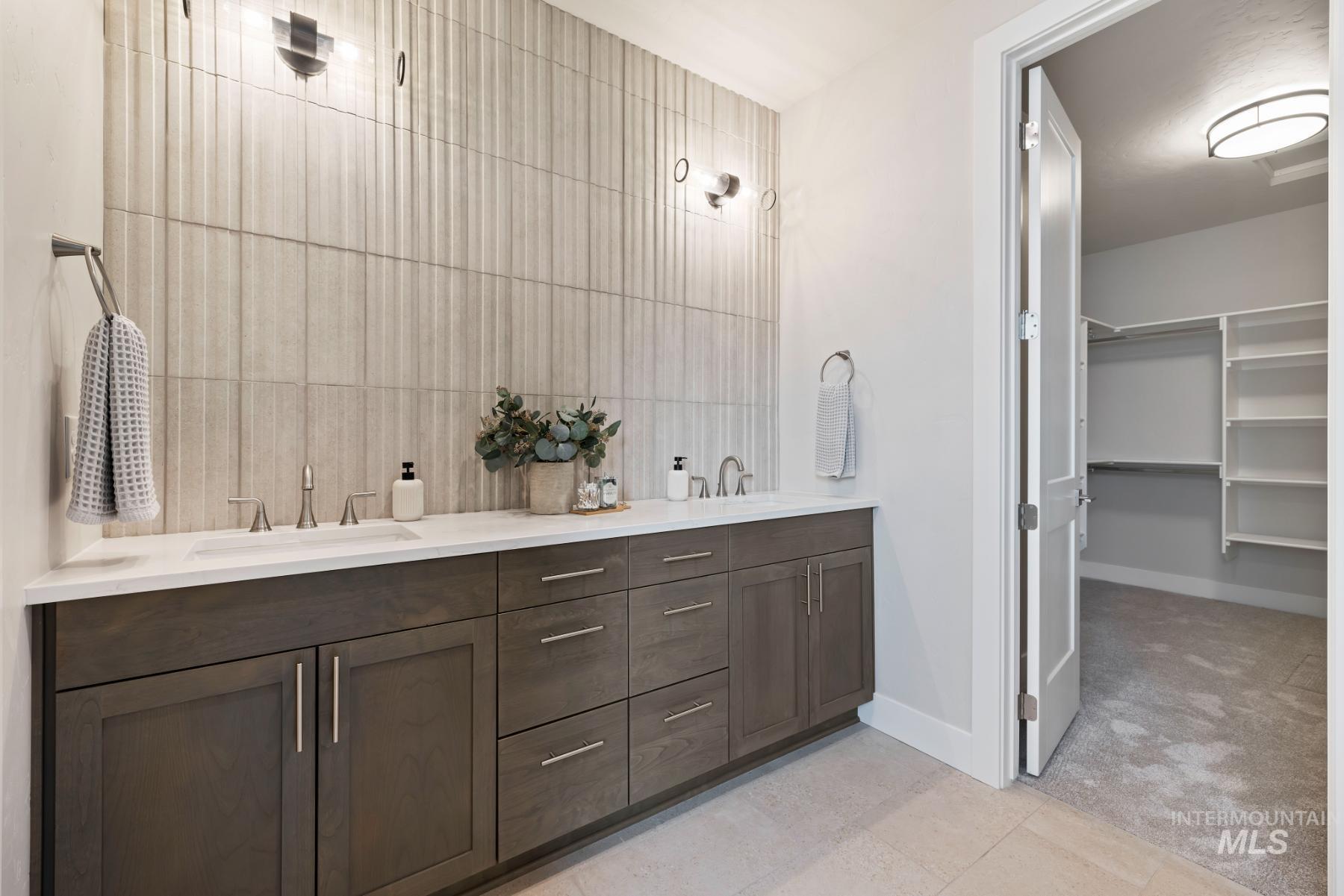 Bathroom with double vanity, light tile patterned flooring, a walk in closet, and light colored carpet