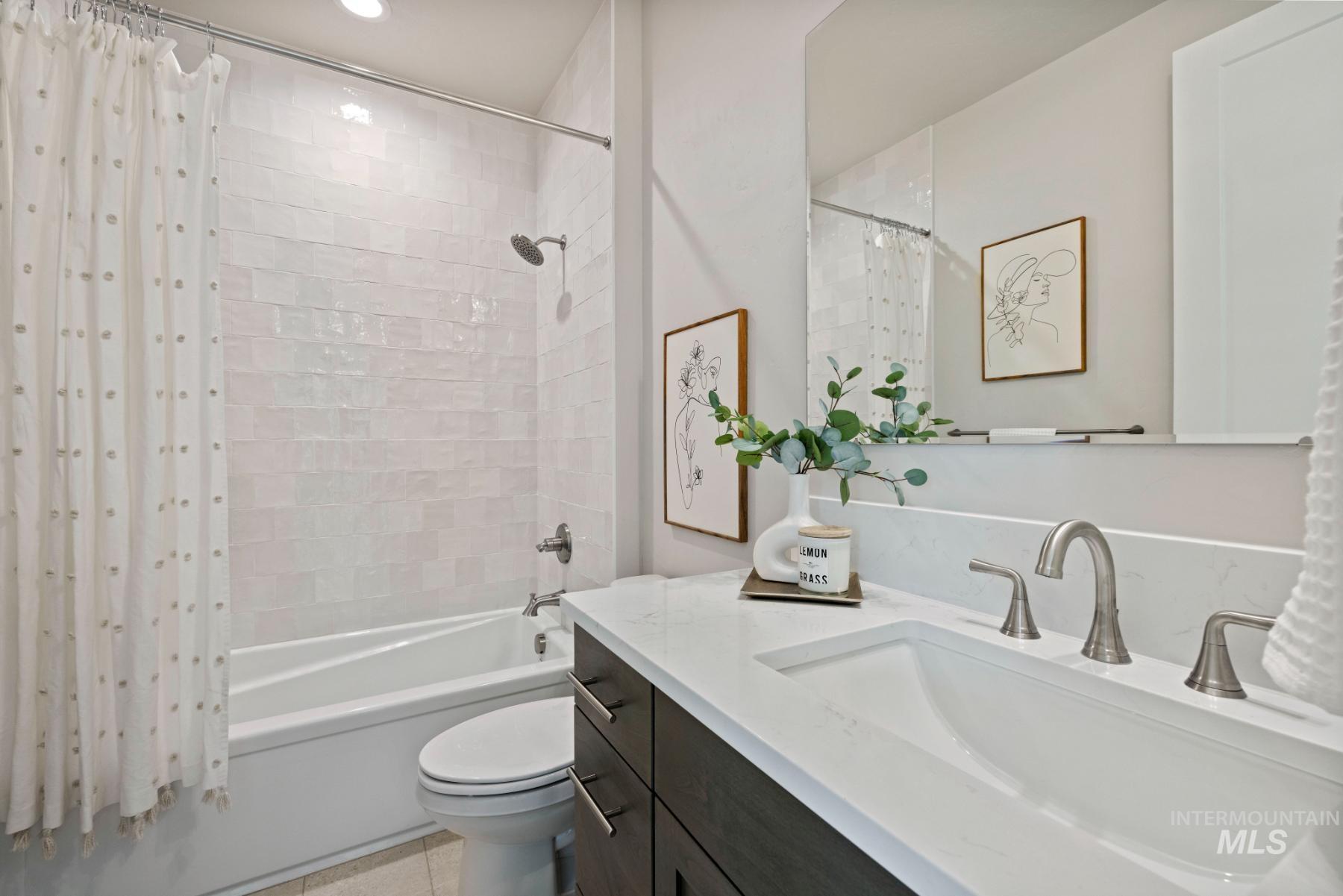 Full bathroom featuring vanity, shower / bath combo with shower curtain, and light tile patterned floors