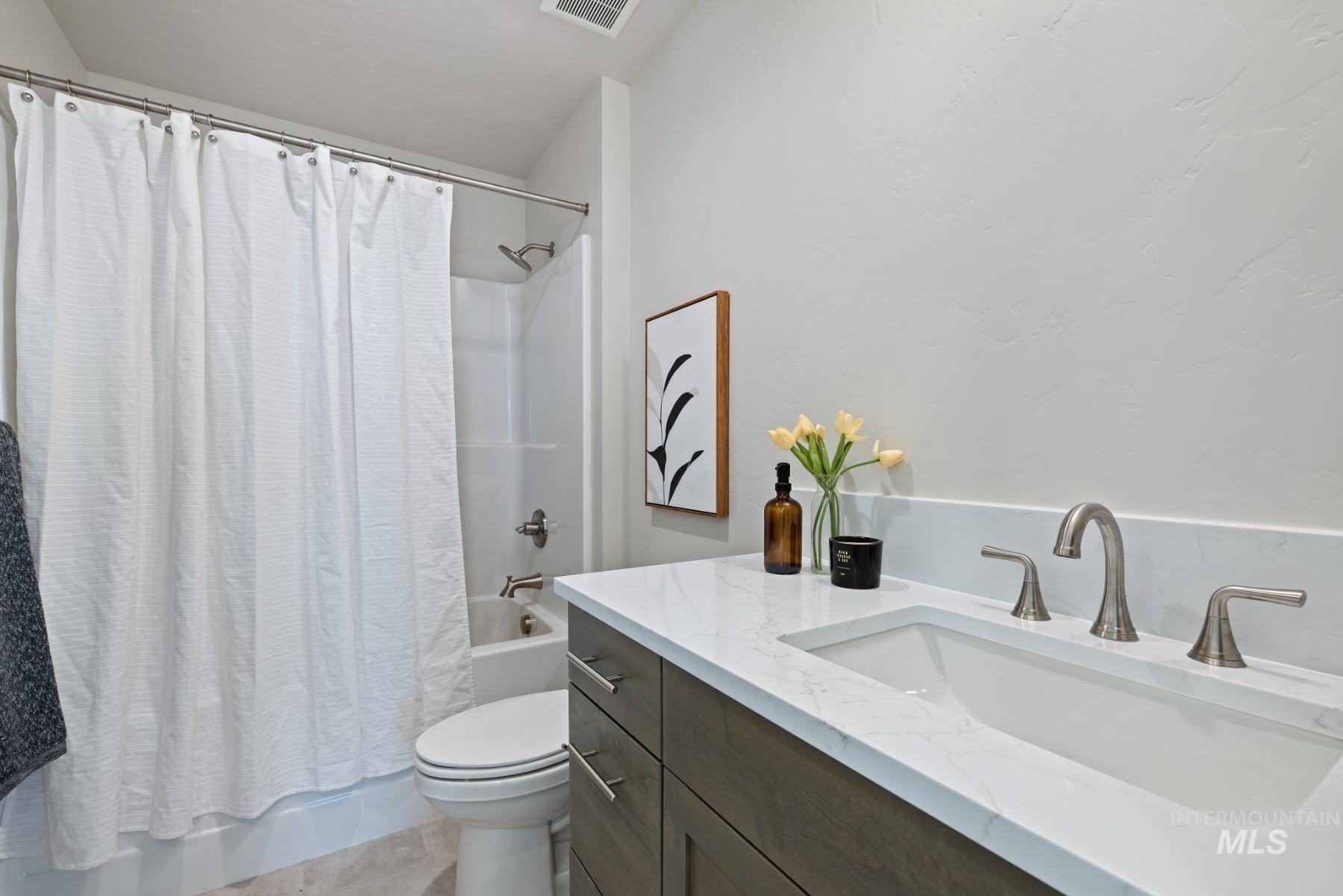 Full bath with shower / tub combo, vanity, and light tile patterned flooring
