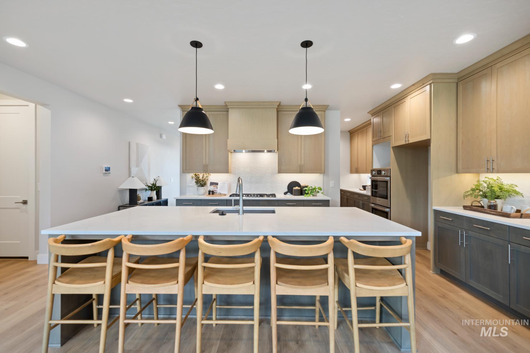 Kitchen with a kitchen breakfast bar, pendant lighting, light wood finished floors, a kitchen island with sink, and recessed lighting