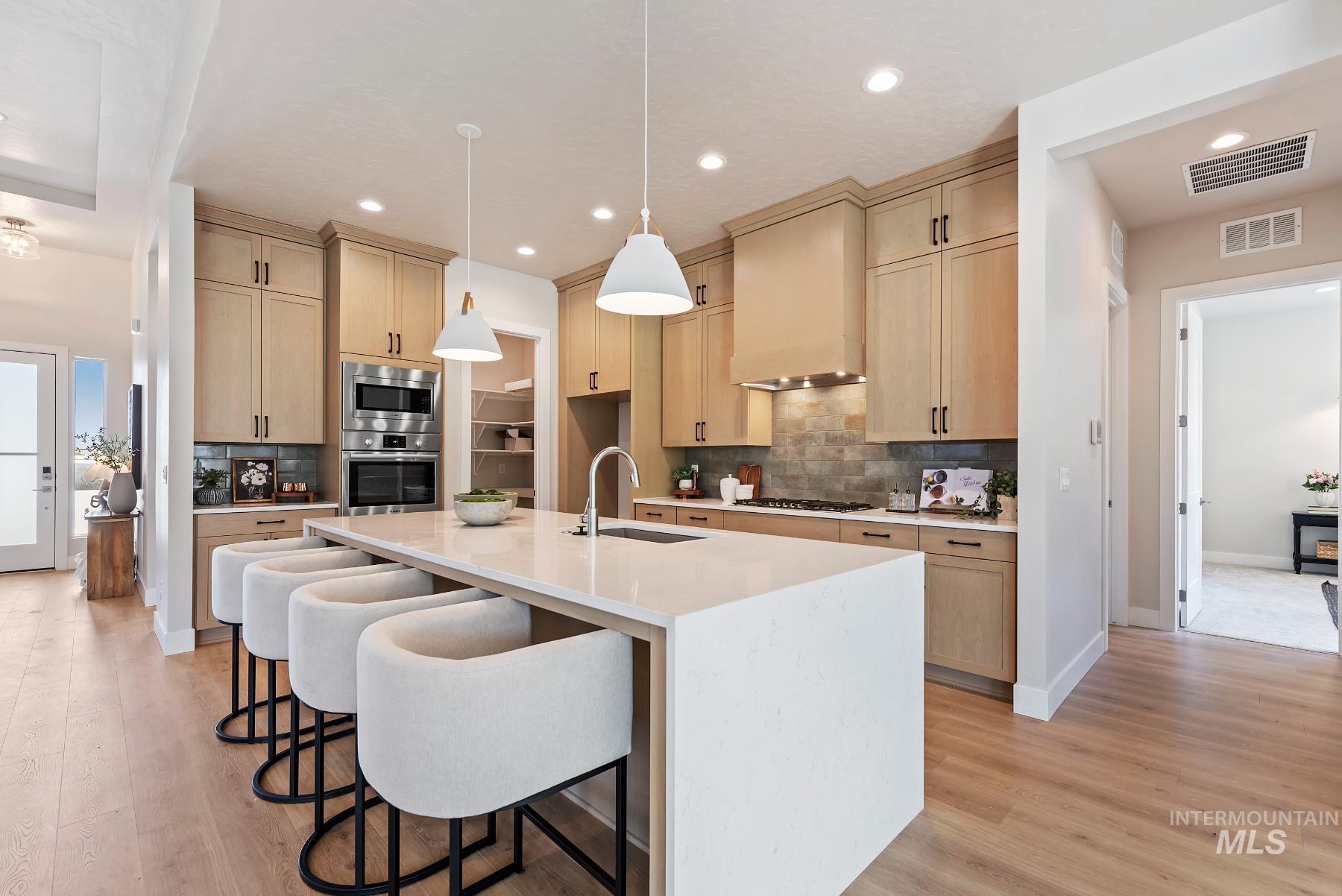 Kitchen featuring light stone counters, a breakfast bar area, decorative backsplash, pendant lighting, and recessed lighting