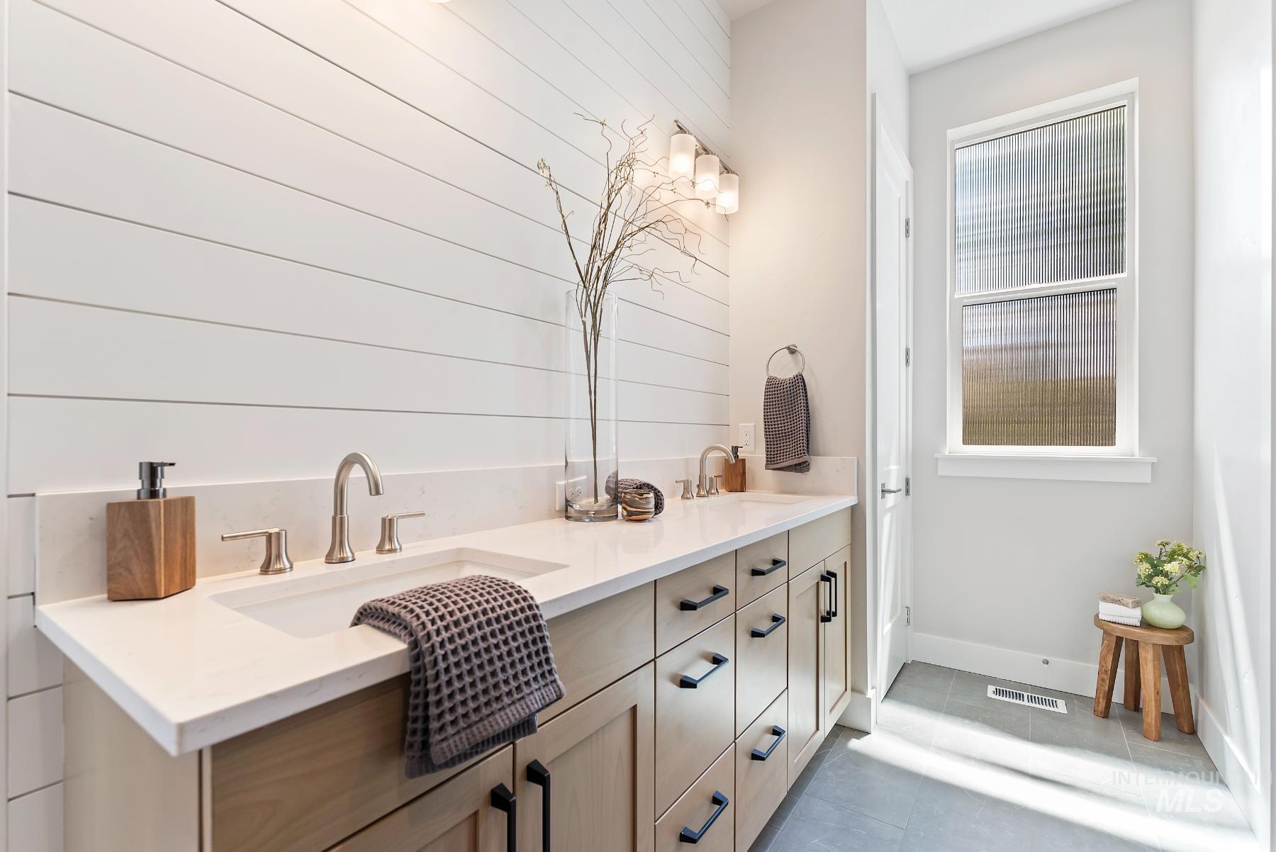 Bathroom with double vanity and light tile patterned floors