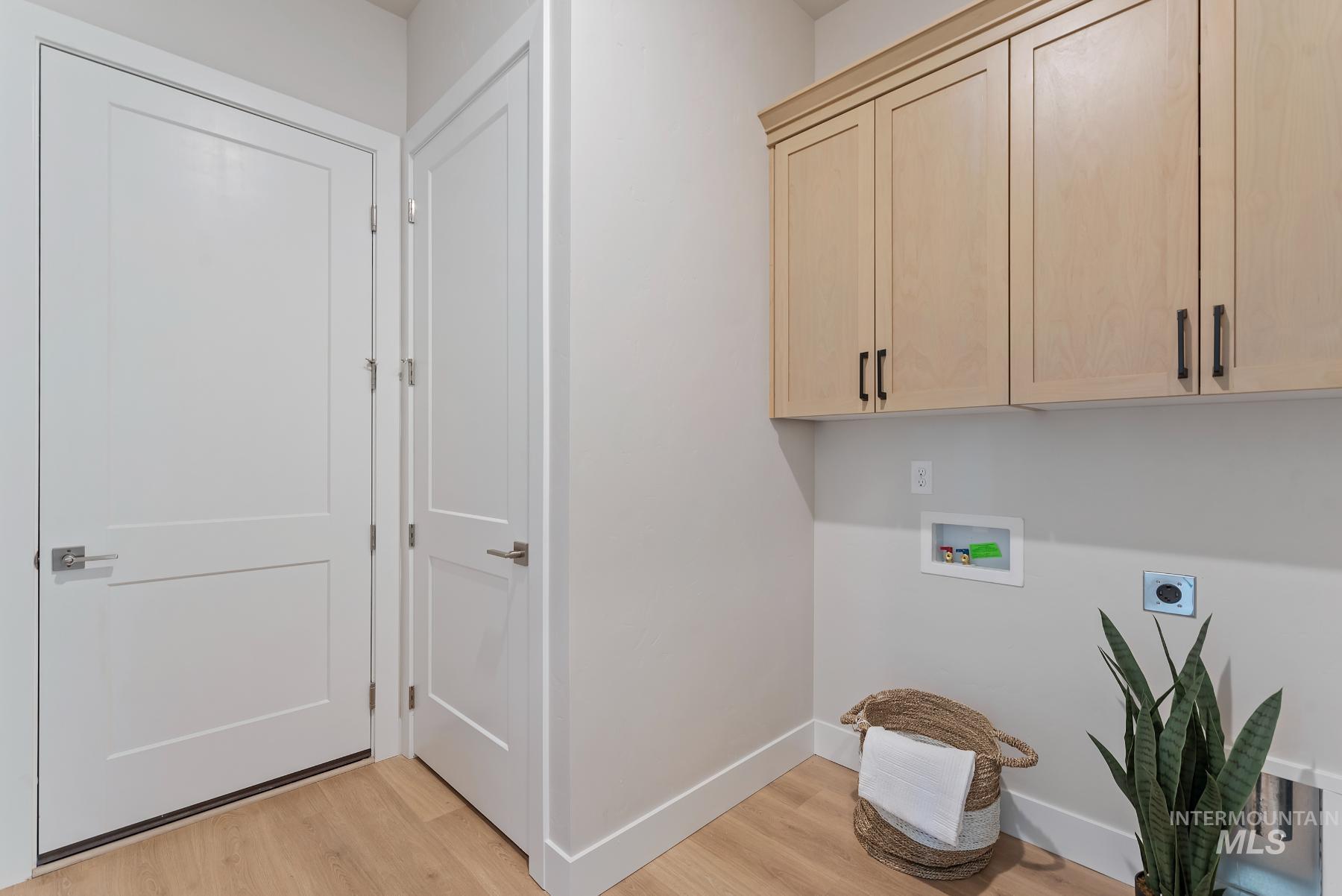 Laundry area featuring light wood-type flooring, cabinet space, washer hookup, and electric dryer hookup