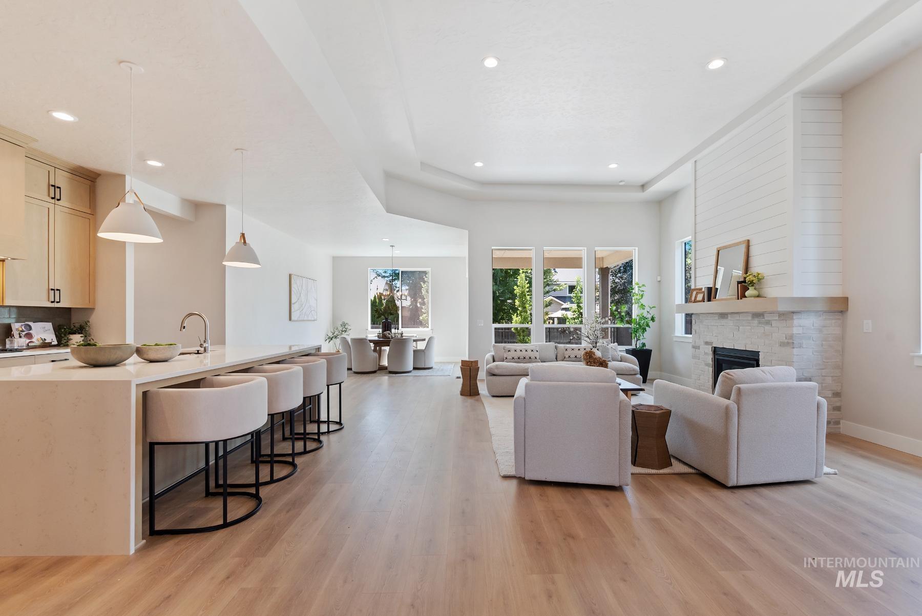 Living area featuring a fireplace, light wood-style floors, a raised ceiling, and recessed lighting