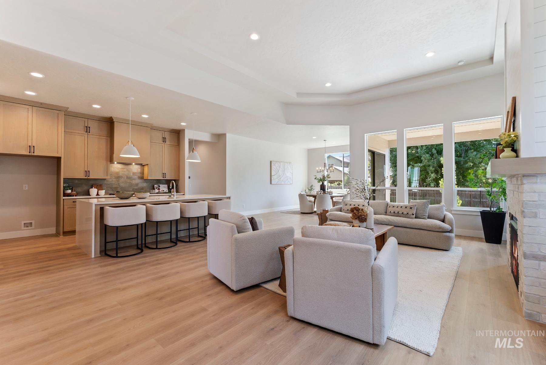 Living area featuring recessed lighting, light wood-style flooring, a raised ceiling, and a fireplace