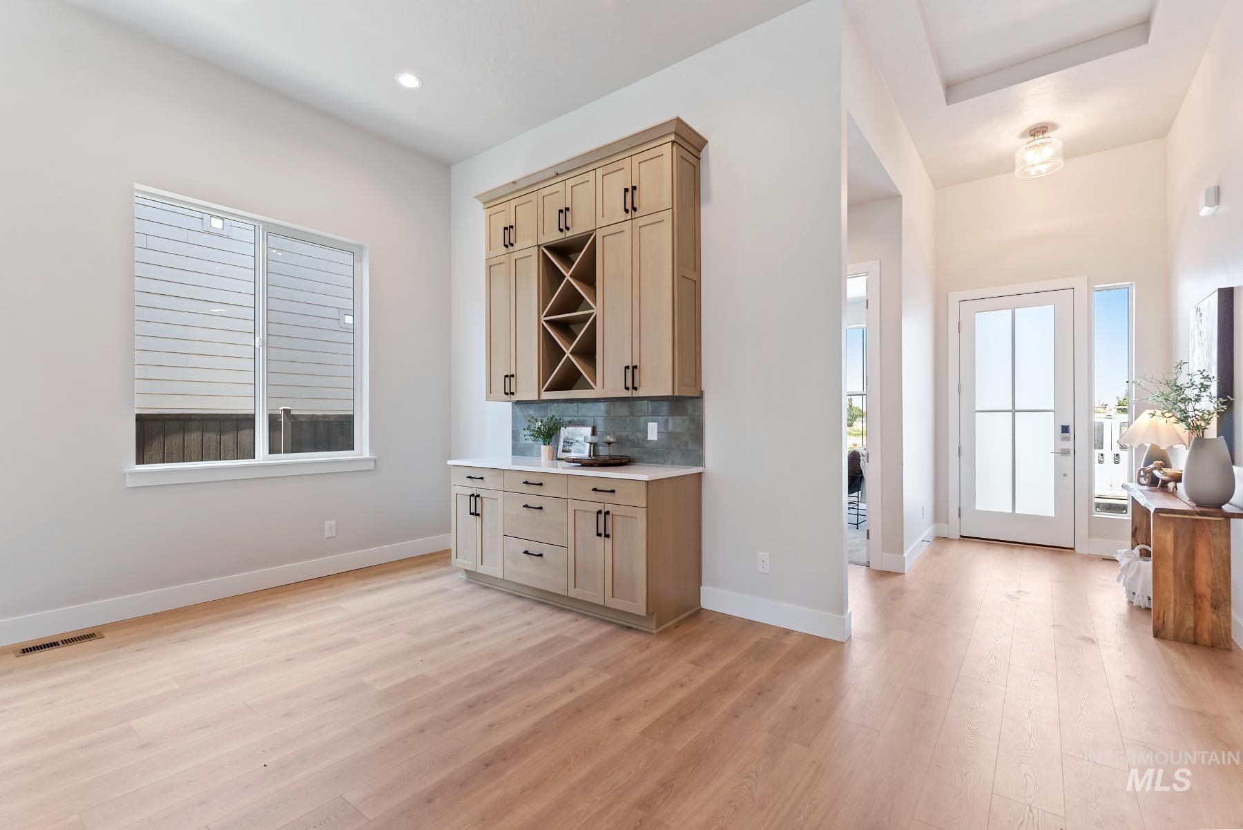 Bar with backsplash, light wood-style flooring, light brown cabinetry, light stone countertops, and recessed lighting