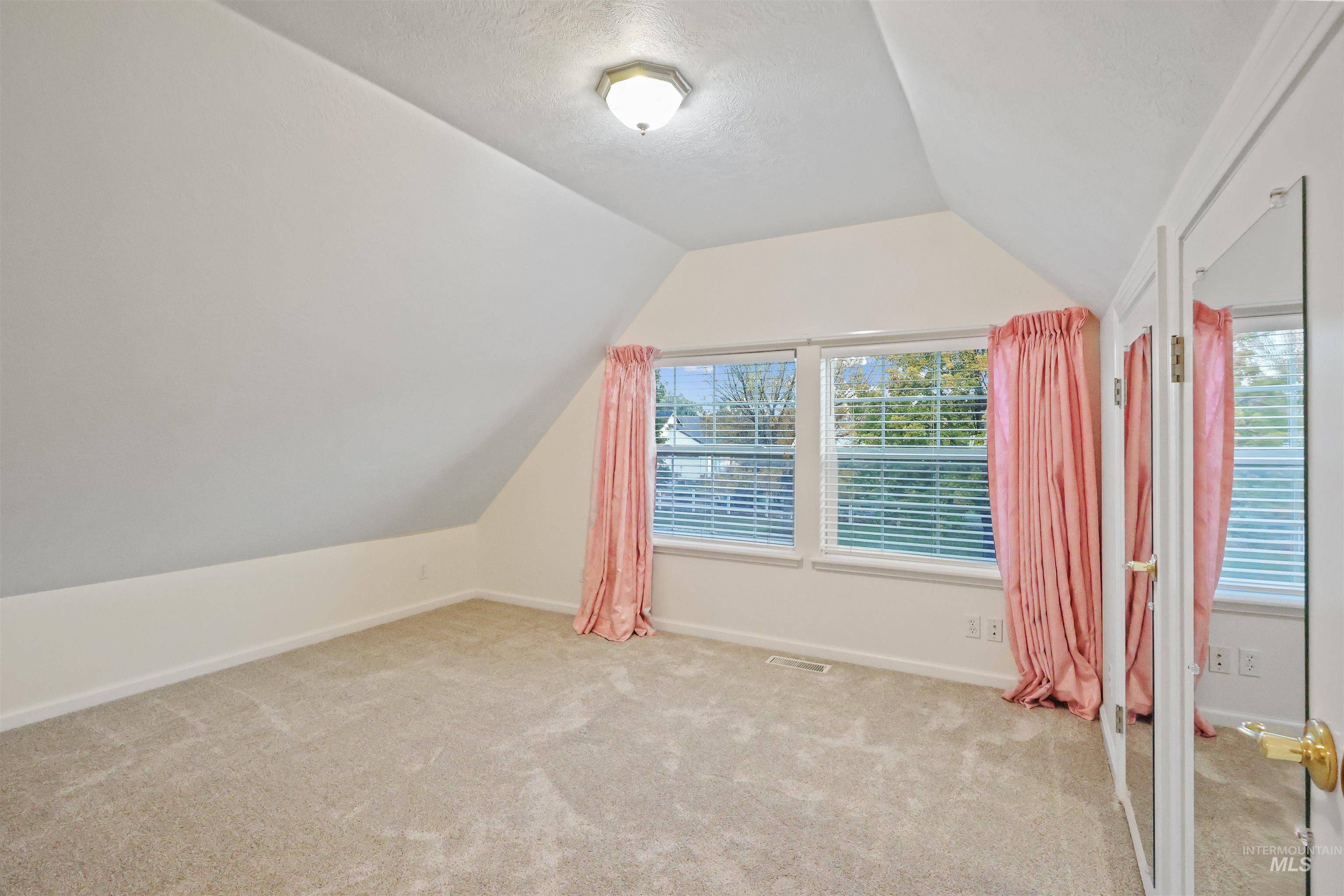 Additional living space featuring lofted ceiling and light carpet