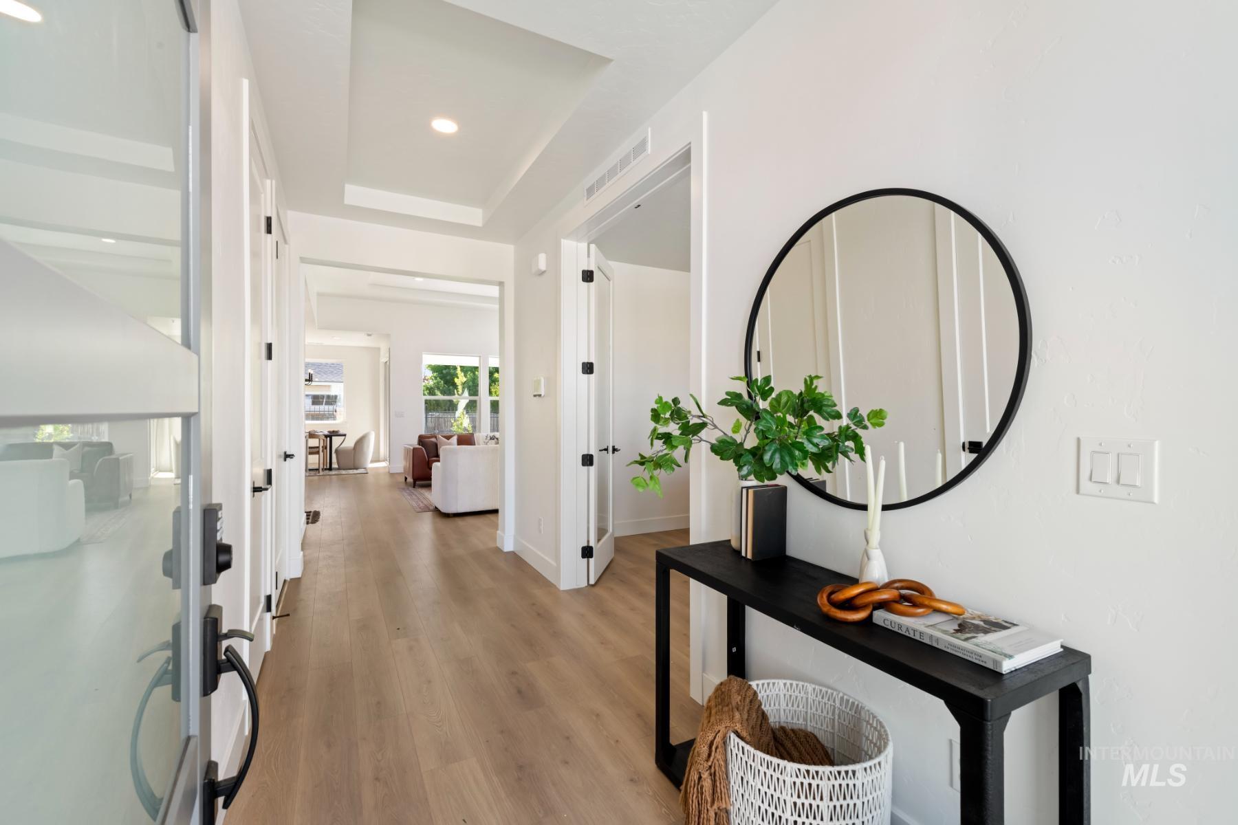 Corridor featuring light wood-style floors, a tray ceiling, and recessed lighting