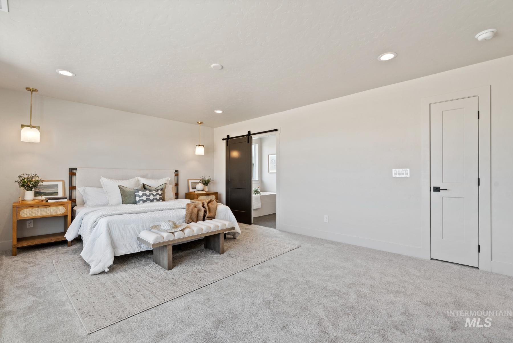 Carpeted bedroom with a barn door, recessed lighting, and ensuite bath