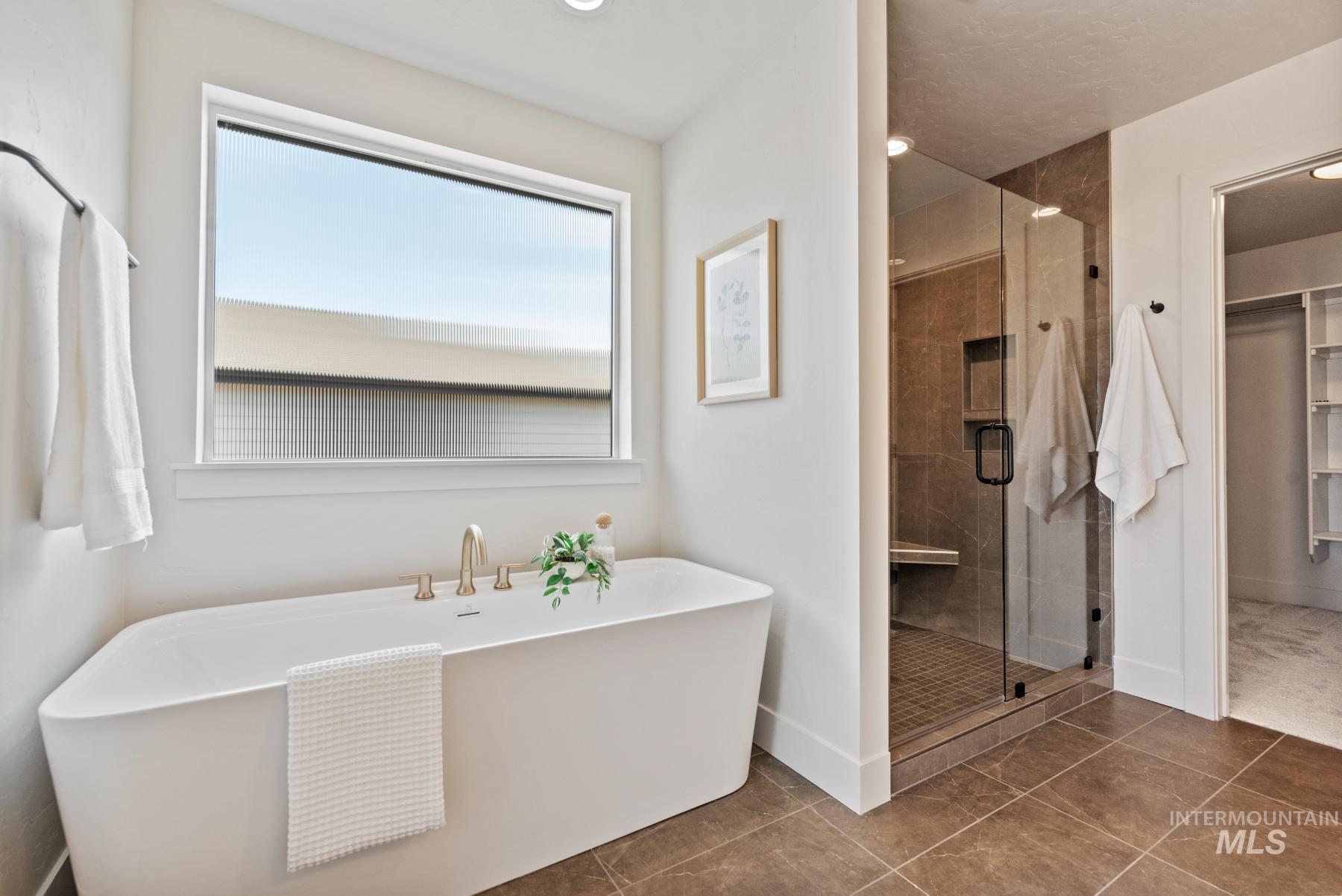 Bathroom featuring a shower stall, a soaking tub, a walk in closet, tile patterned flooring, and recessed lighting