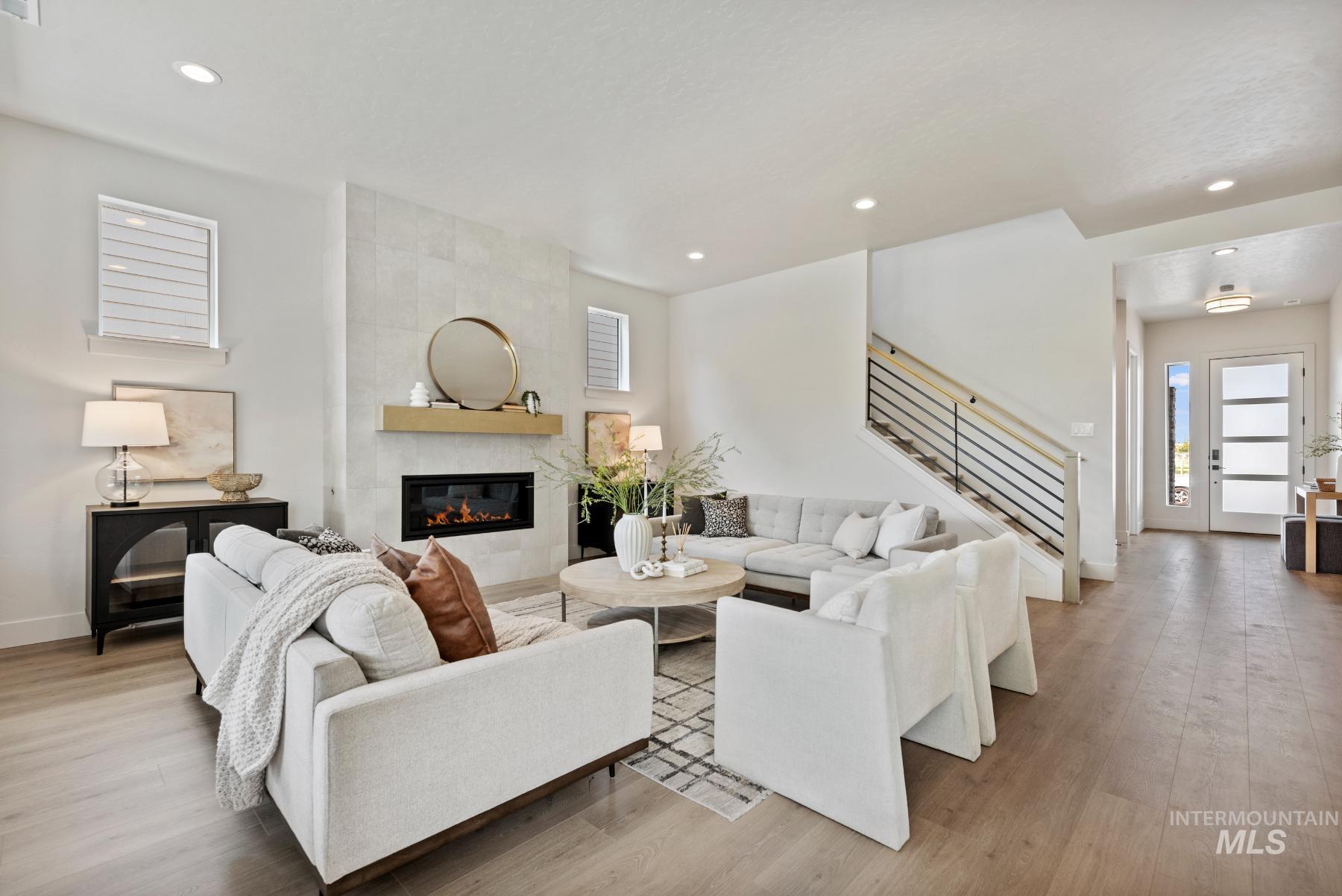 Living room with stairway, a fireplace, light wood finished floors, and recessed lighting