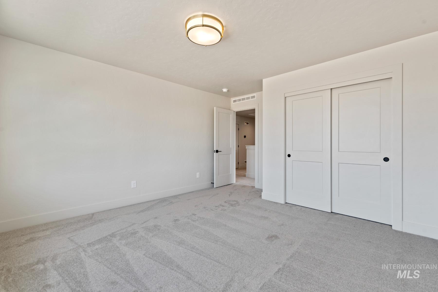 Unfurnished bedroom with light colored carpet and a closet