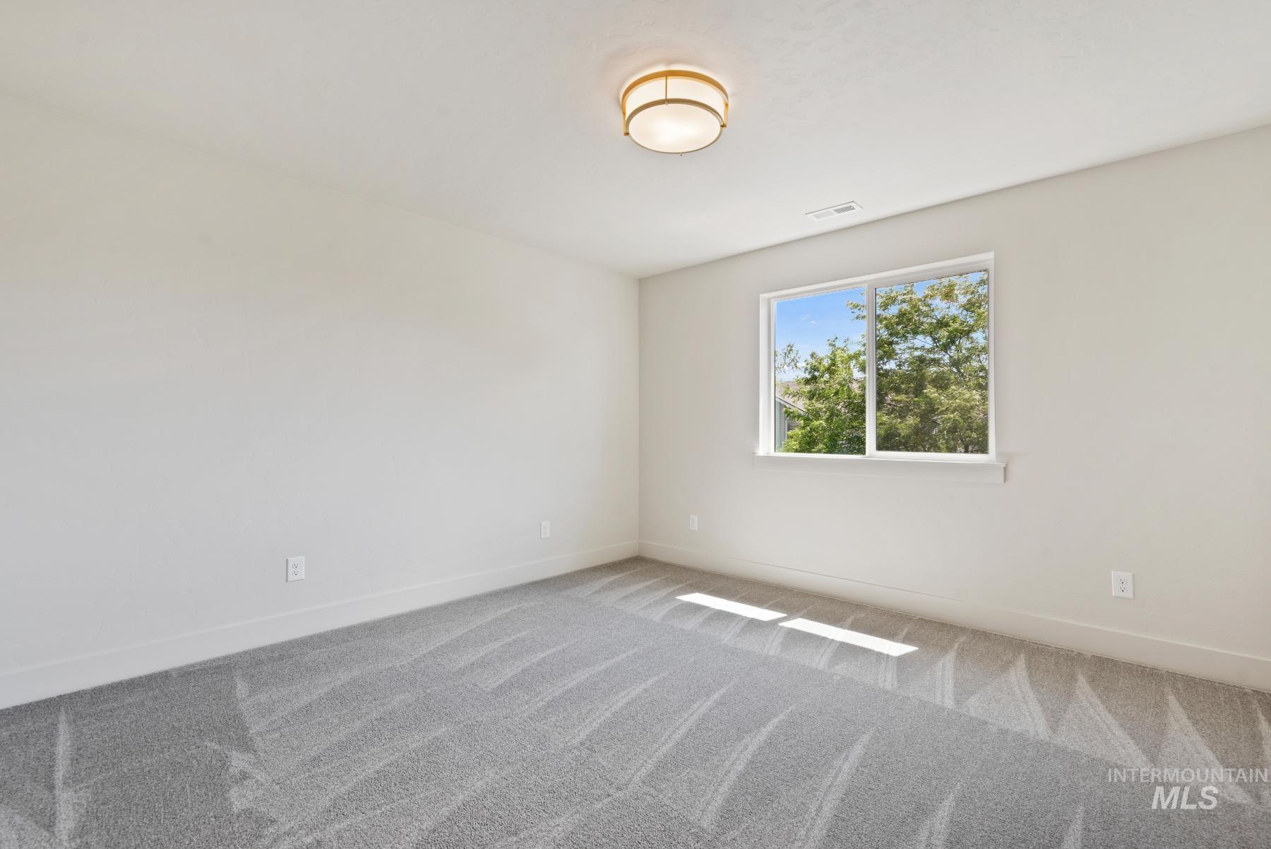 Carpeted spare room featuring baseboards