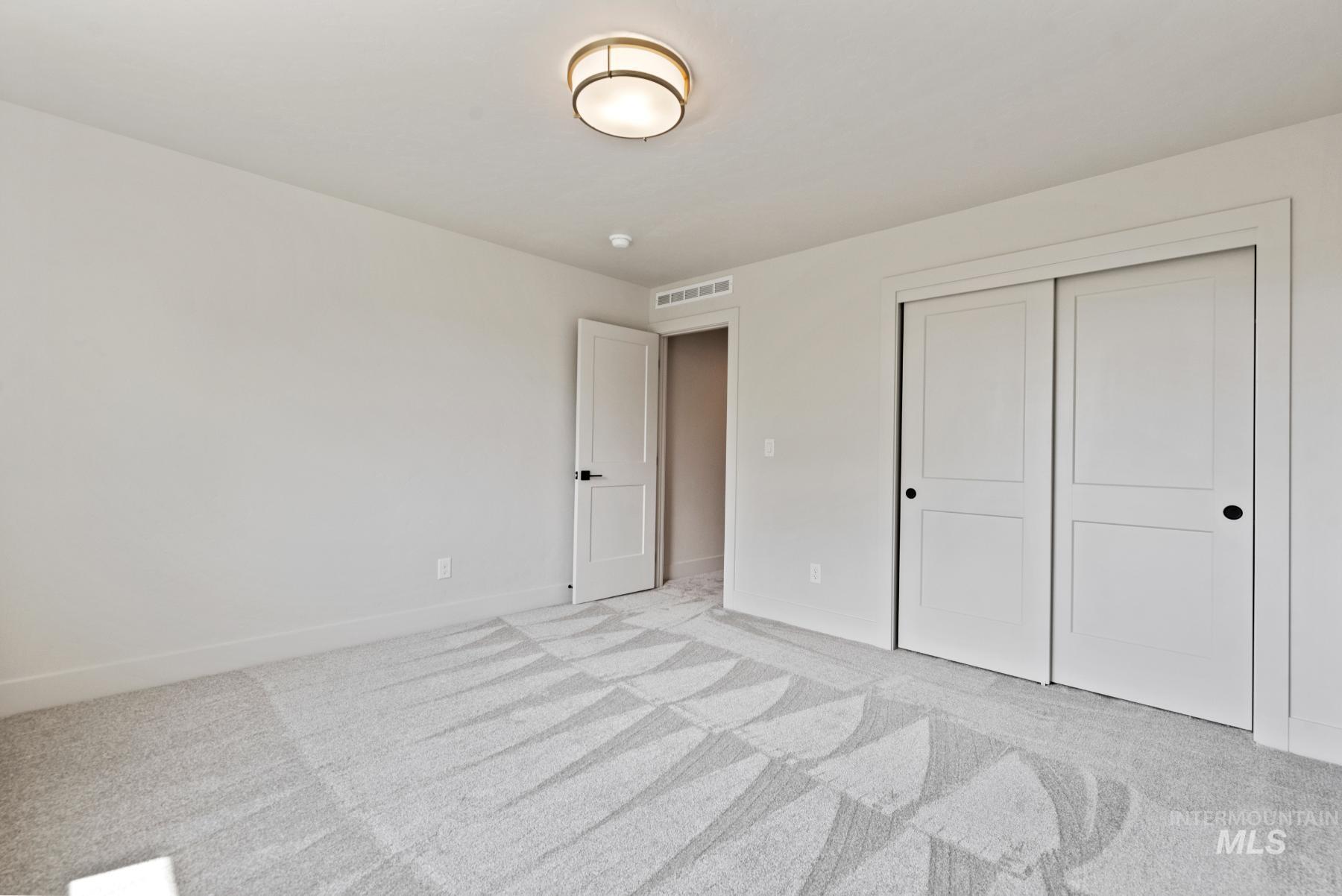 Unfurnished bedroom with light colored carpet and a closet