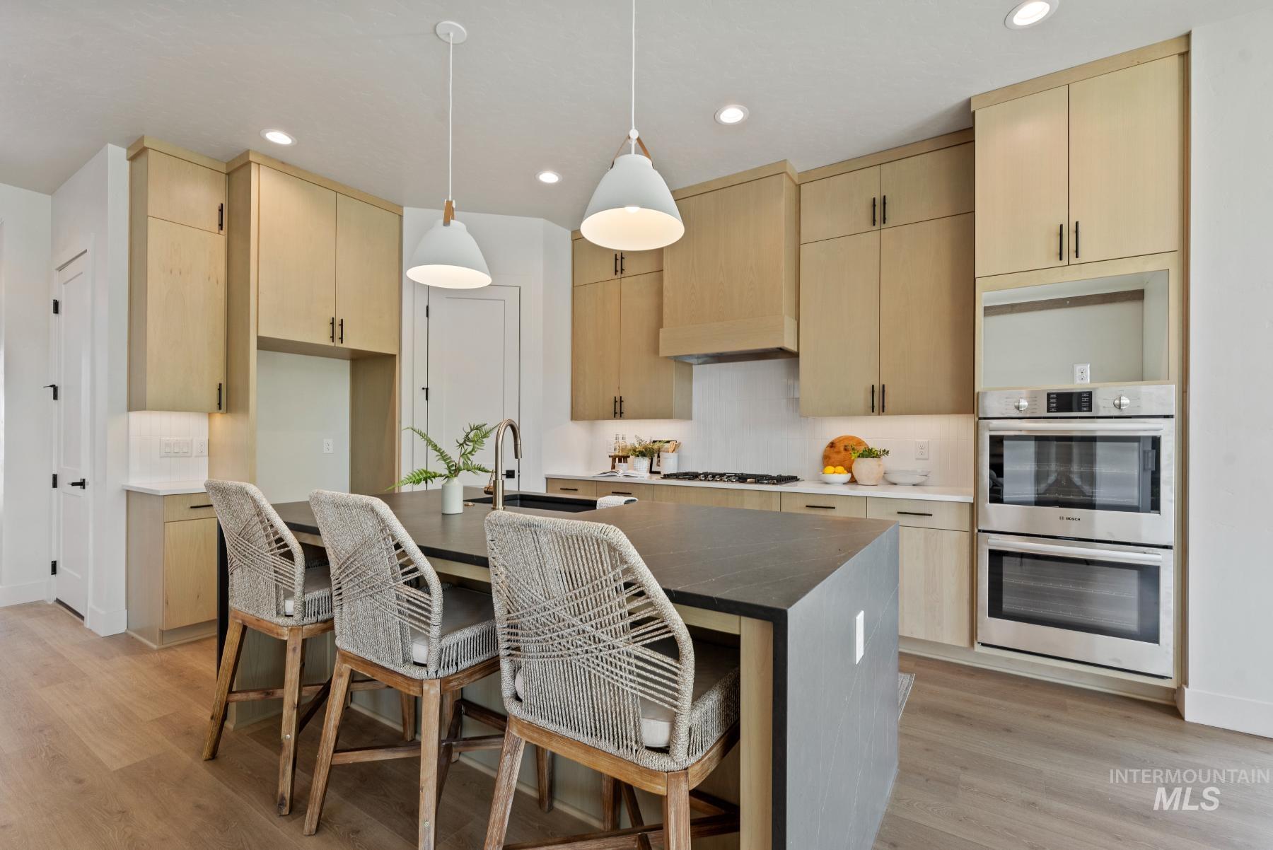 Kitchen featuring light brown cabinets, pendant lighting, backsplash, and recessed lighting