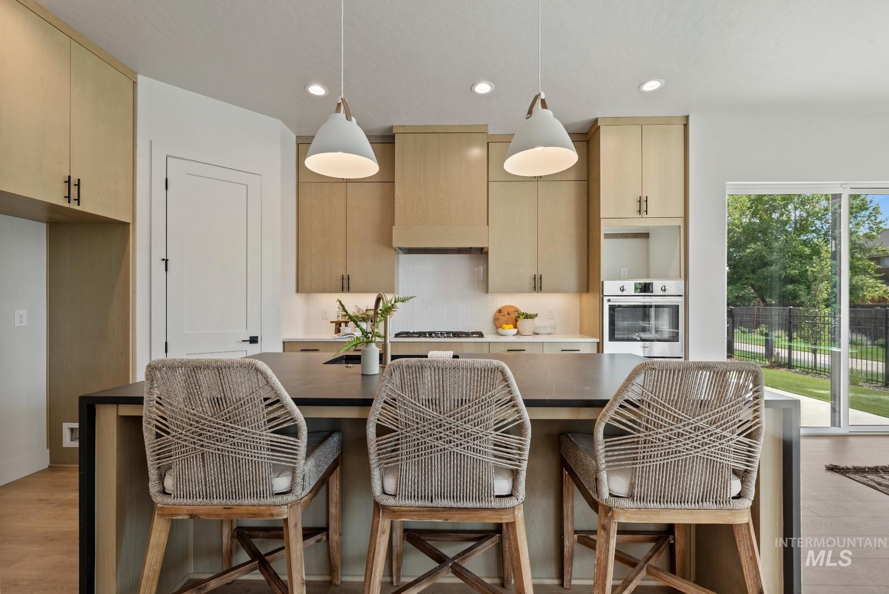 Kitchen with light wood-style flooring, pendant lighting, recessed lighting, a kitchen island, and stainless steel oven