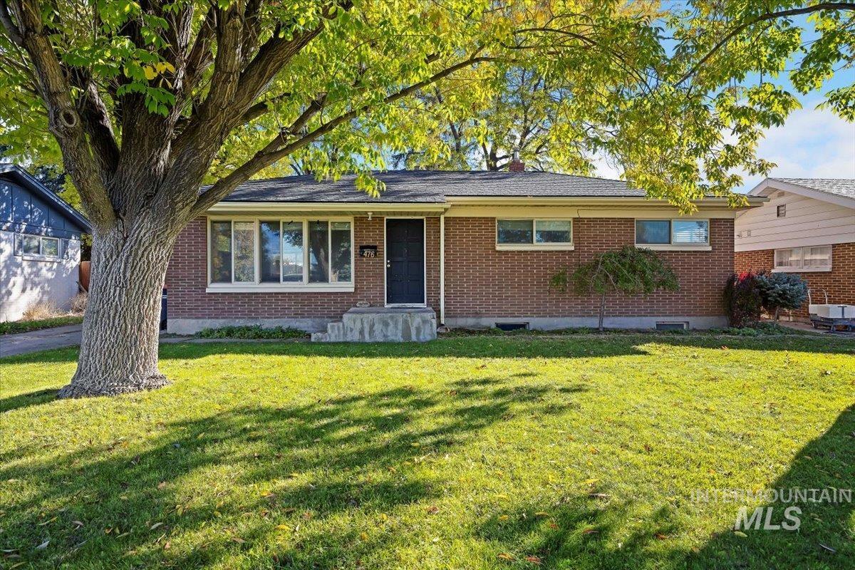 Single story home with a front lawn and brick siding