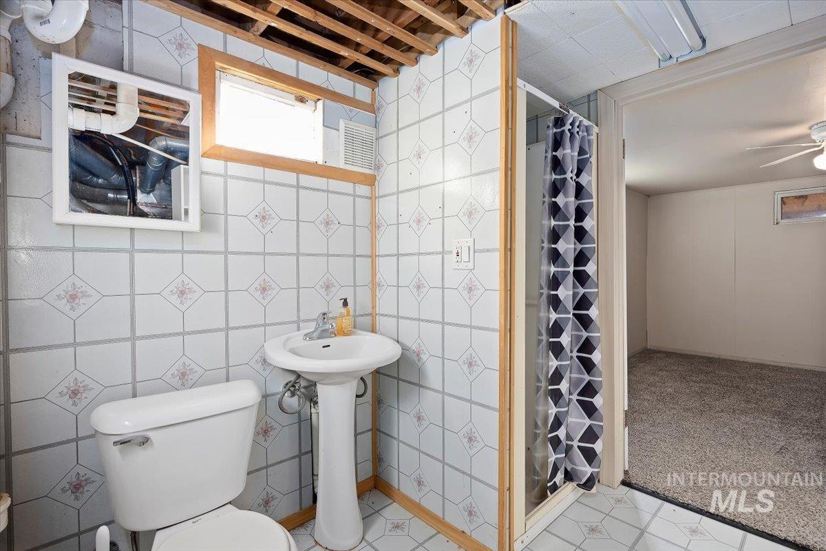 Full bathroom with a stall shower, light colored carpet, ceiling fan, and tile walls
