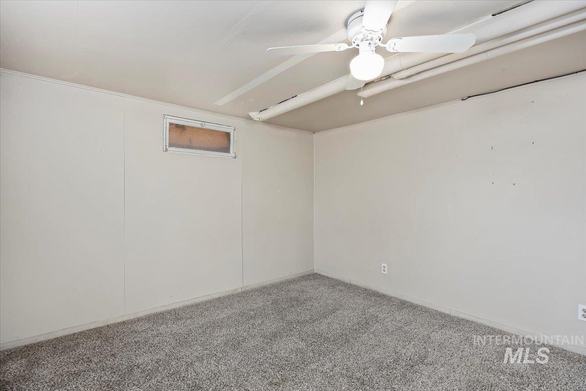 Carpeted spare room featuring ceiling fan and baseboards
