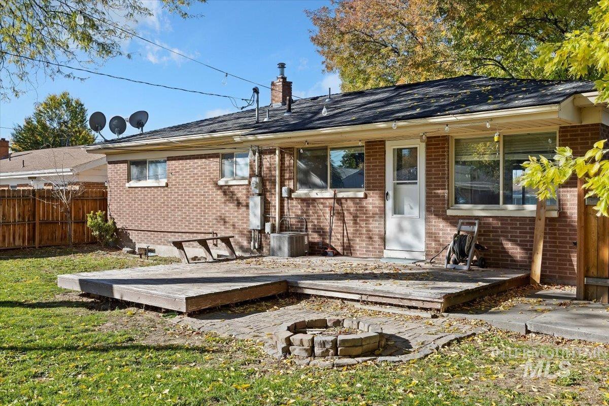 Back of property featuring an outdoor fire pit, brick siding, and a chimney