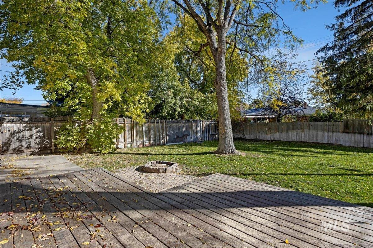 Deck with an outdoor fire pit and a fenced backyard