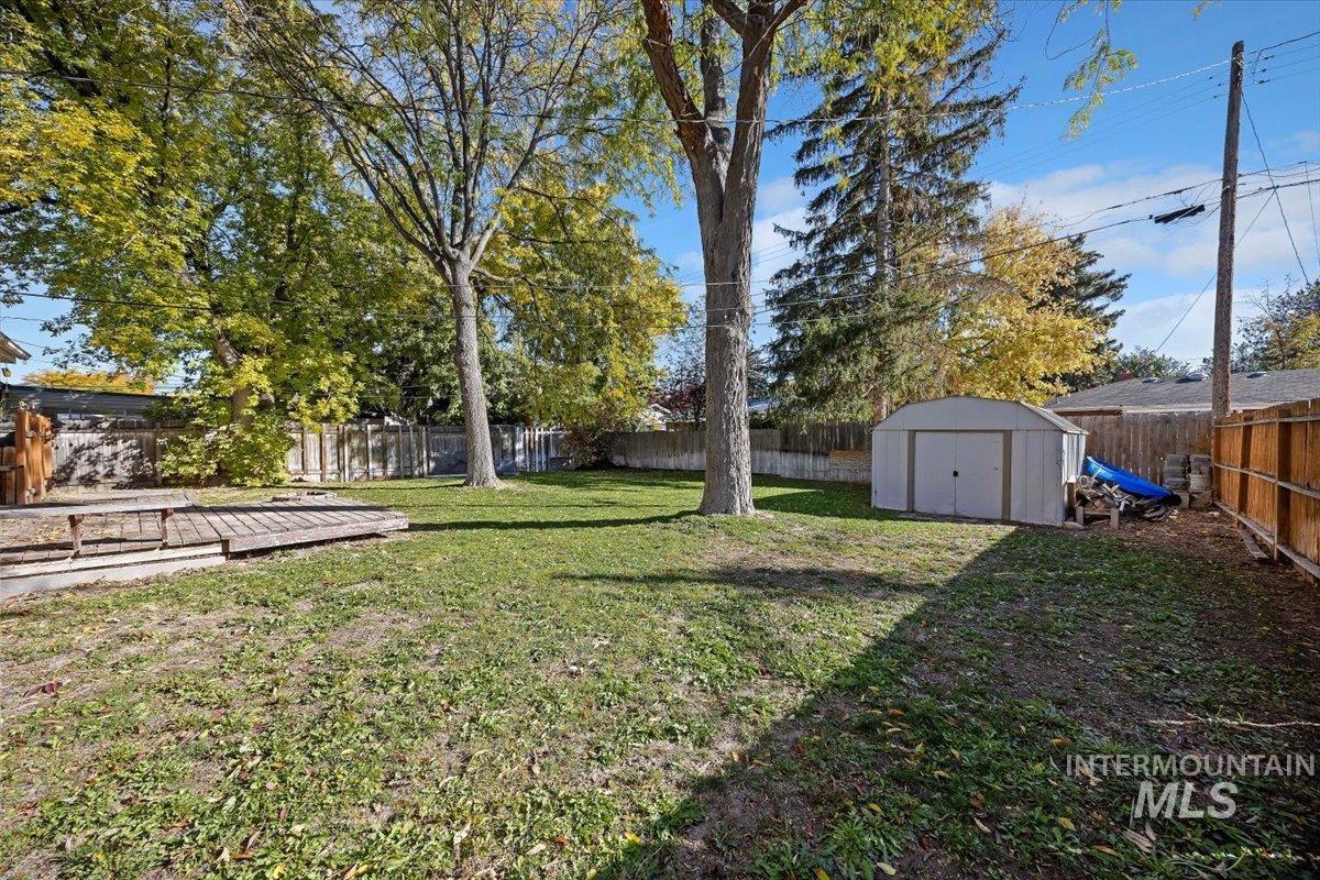 Fenced backyard featuring a storage shed and a wooden deck