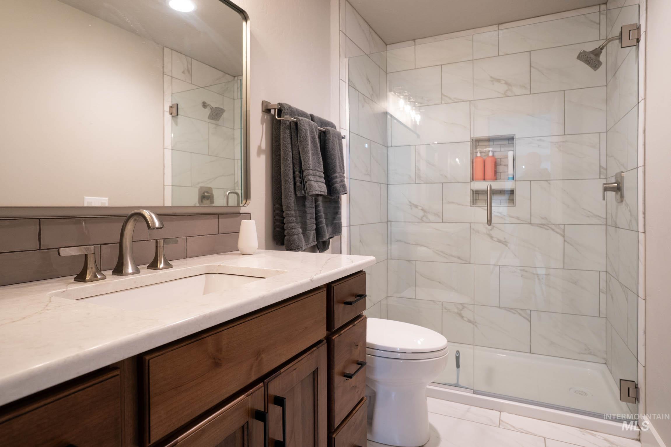 second bathroom on main level with custom tile walk-in shower and quartz countertop