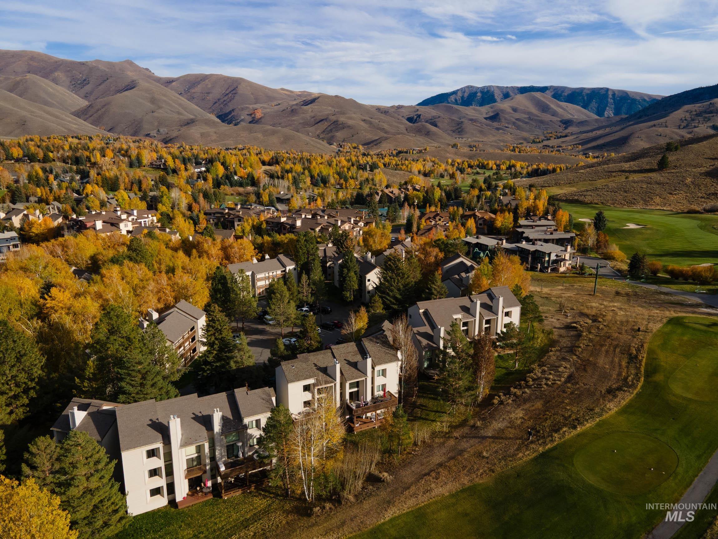 Aerial view of property's location featuring a local golf course, mountains, and nearby suburban area