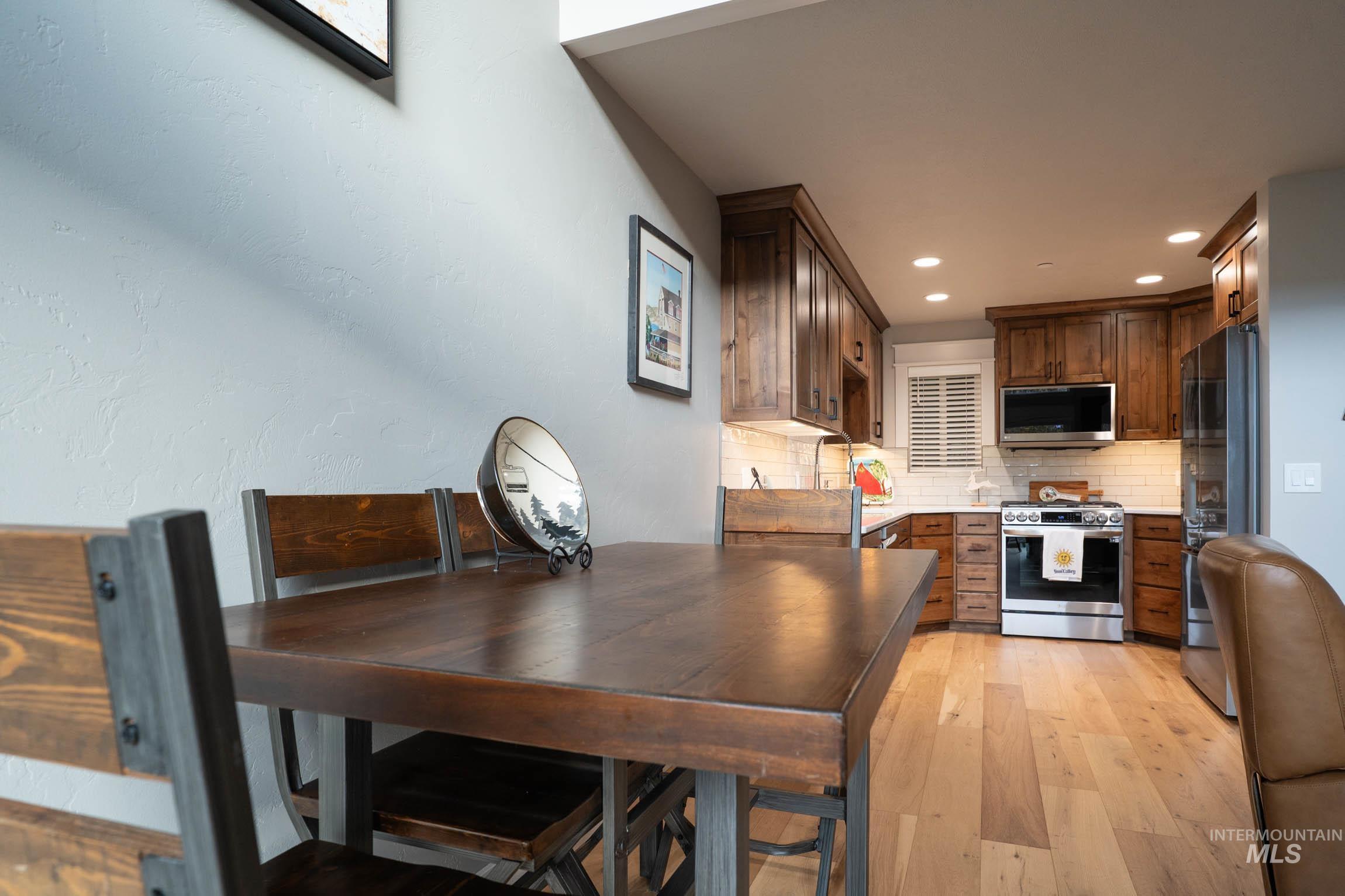 Kitchen featuring backsplash, stainless steel appliances, light wood-type flooring, light countertops, and recessed lighting