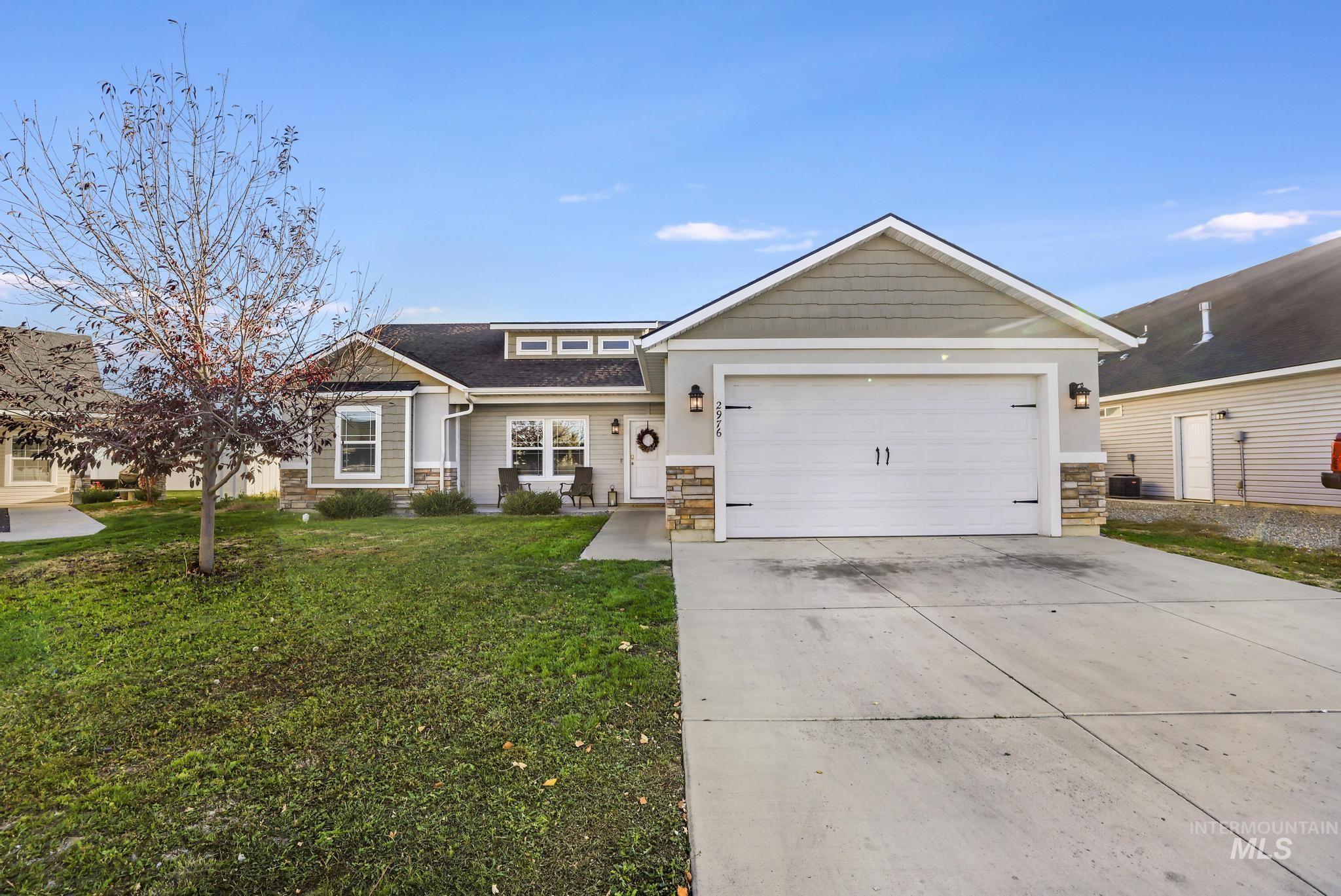 Craftsman inspired home featuring stone siding, driveway, a front lawn, an attached garage, and a shingled roof