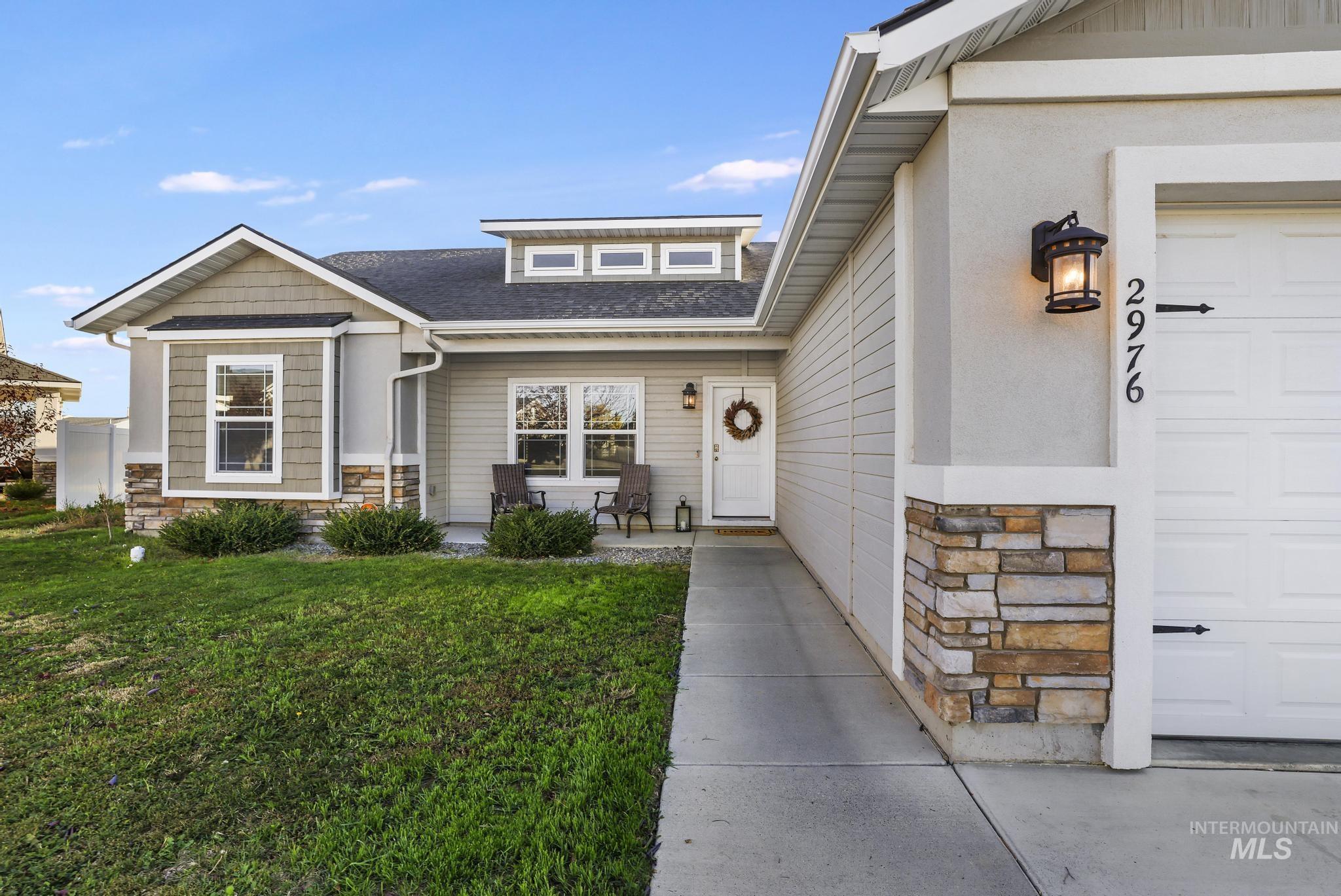 Doorway to property featuring stone siding, a yard, and a shingled roof