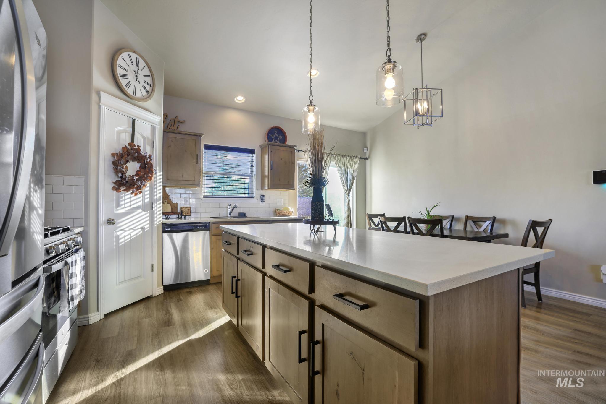 Kitchen featuring tasteful backsplash, appliances with stainless steel finishes, hanging light fixtures, dark wood finished floors, and recessed lighting