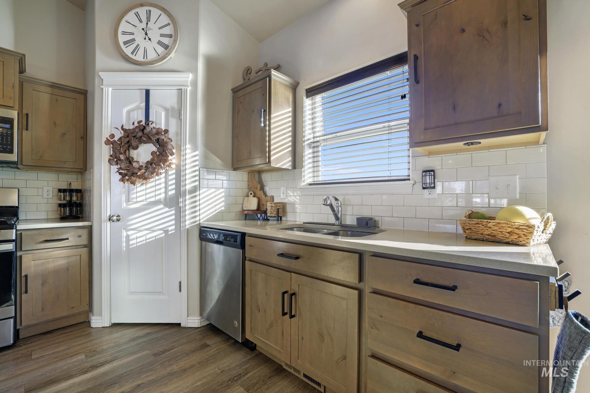 Kitchen with plenty of natural light, appliances with stainless steel finishes, tasteful backsplash, and dark wood-style flooring