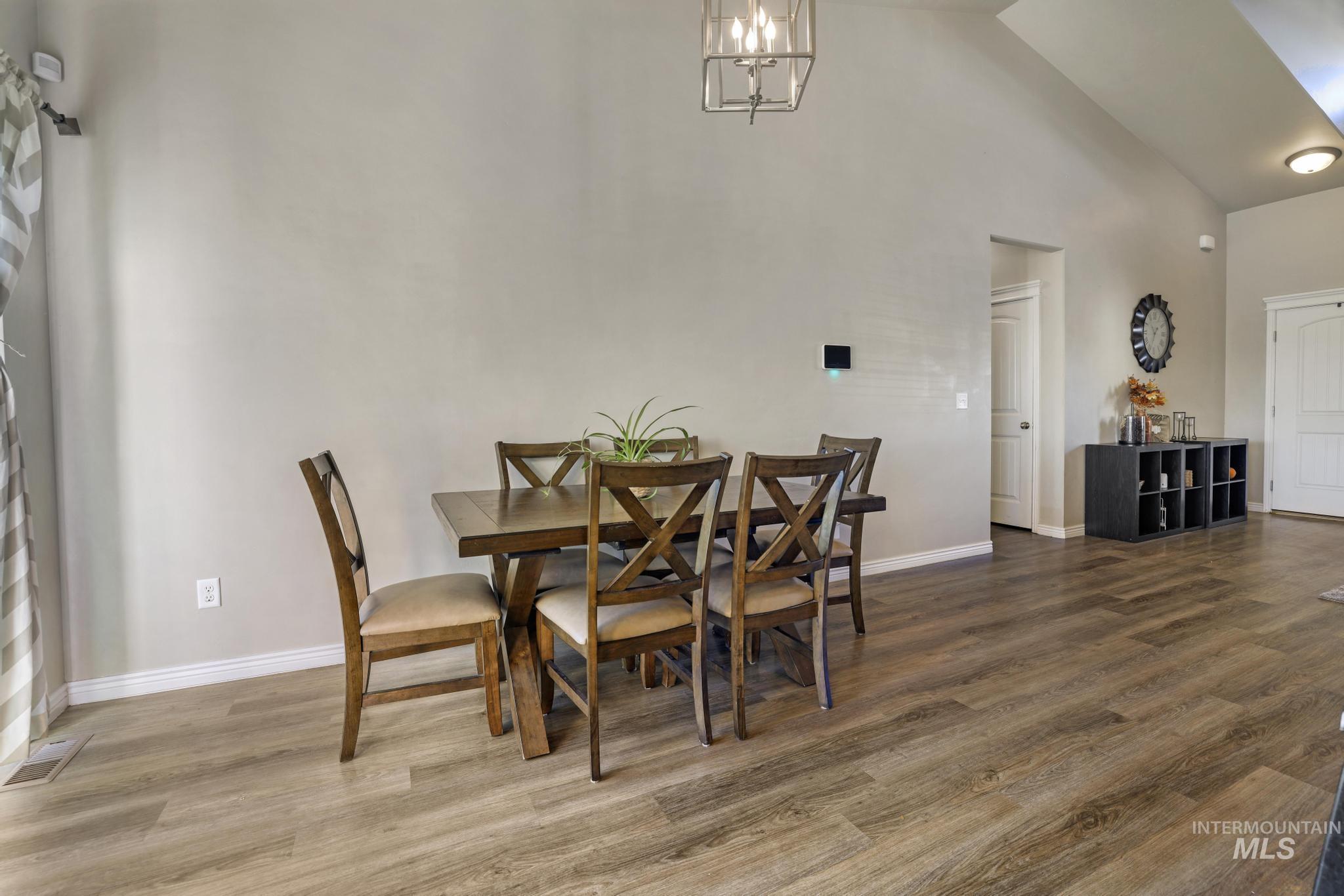 Dining area featuring high vaulted ceiling, wood finished floors, and a chandelier