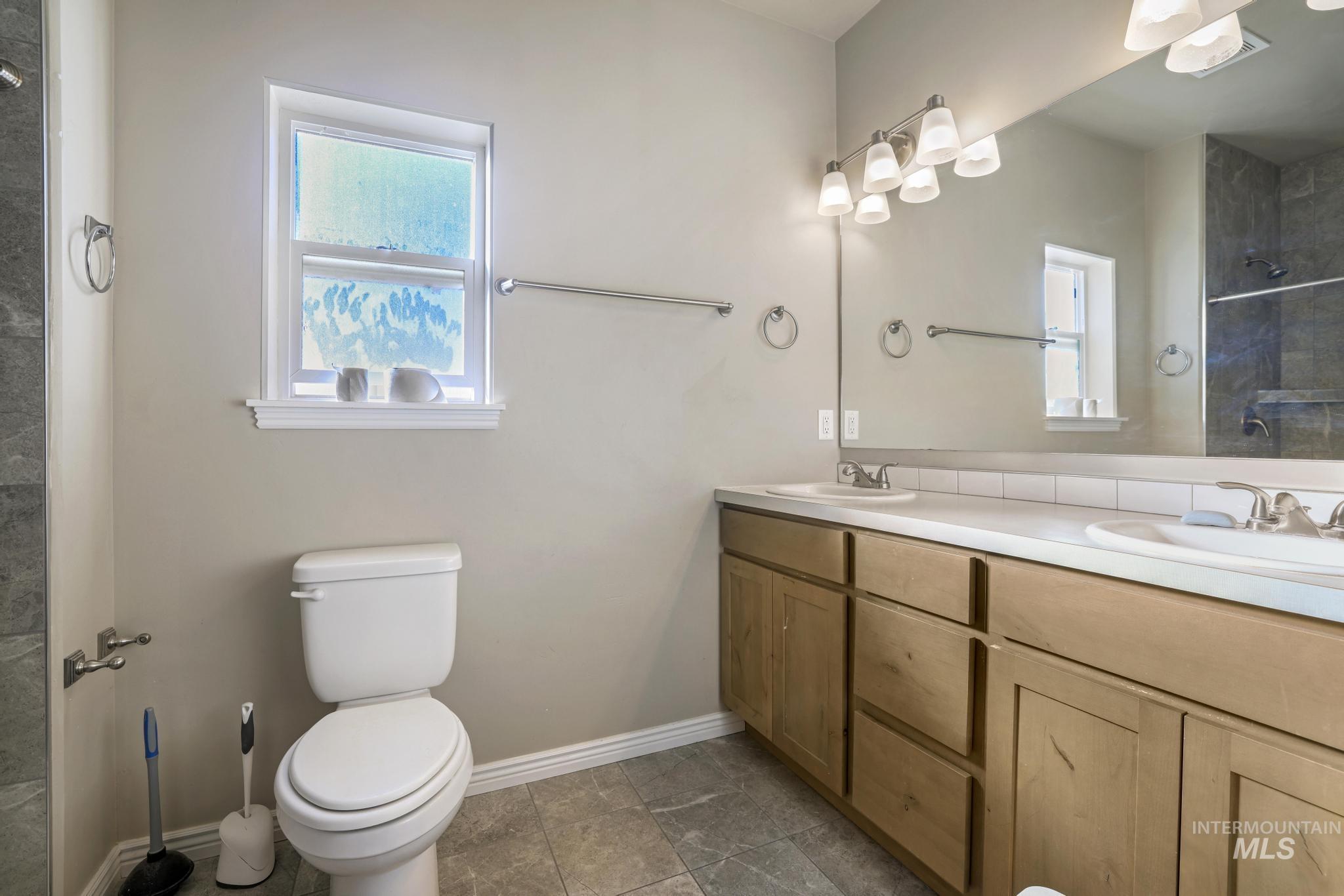 Full bath featuring double vanity and tiled shower