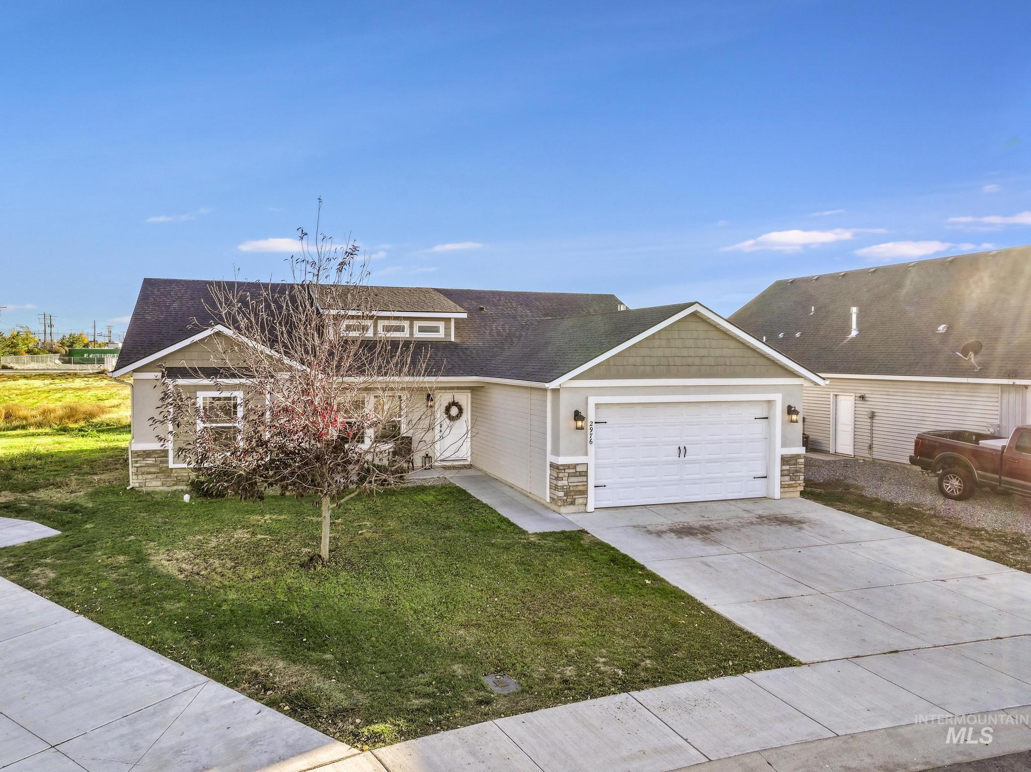 View of front of house with stone siding, a front yard, concrete driveway, and an attached garage