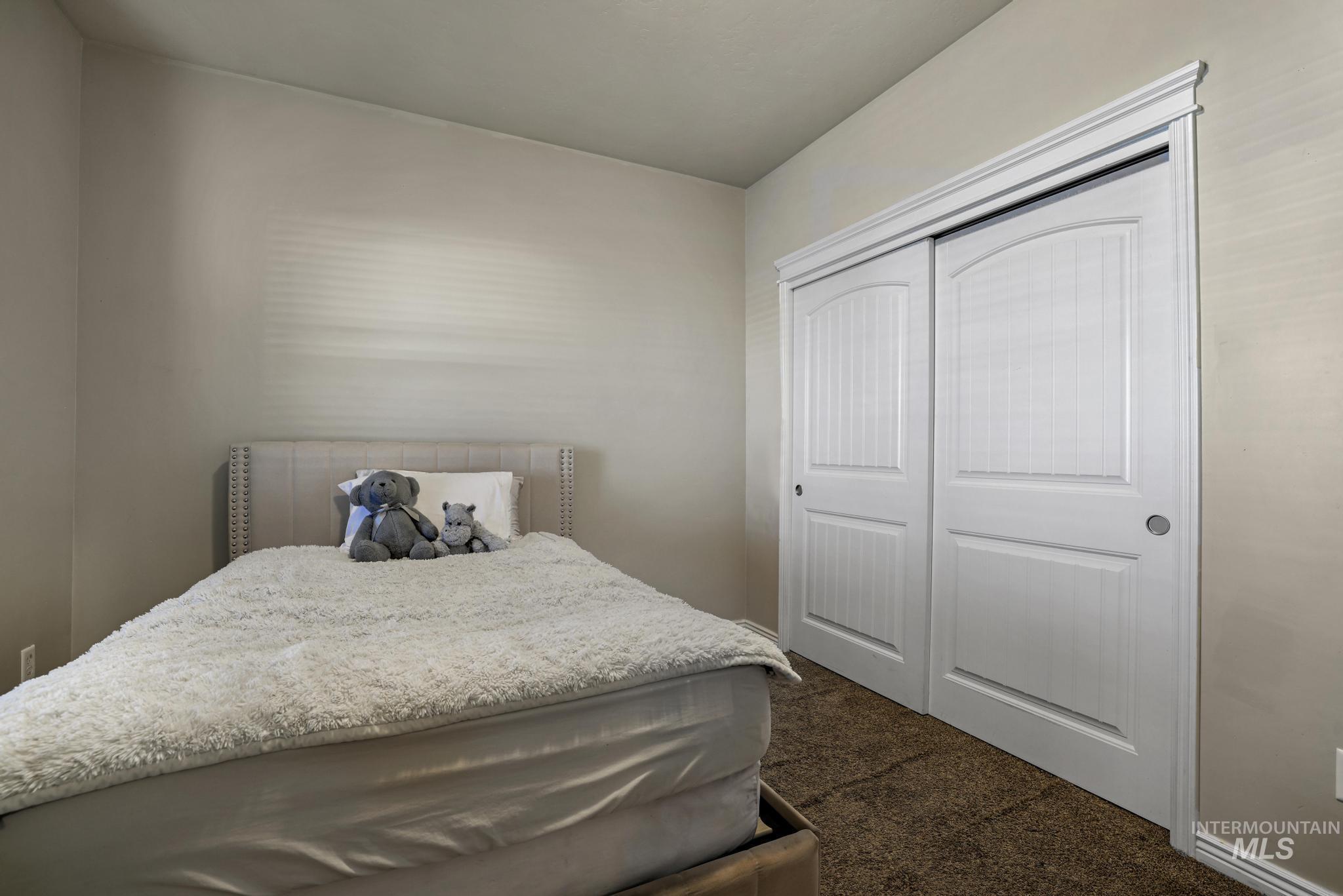 Bedroom with dark colored carpet and a closet