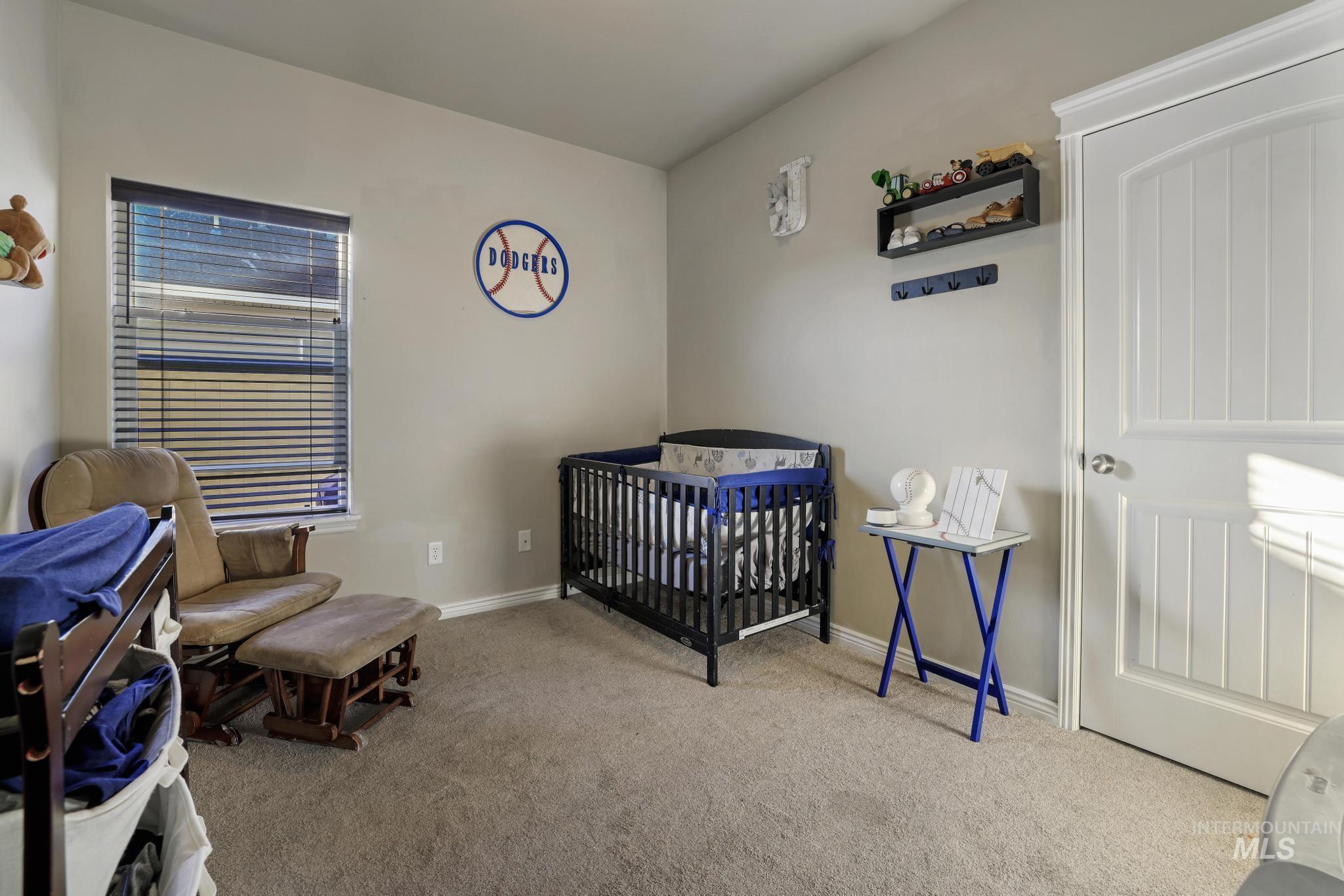 Carpeted bedroom featuring a crib and baseboards