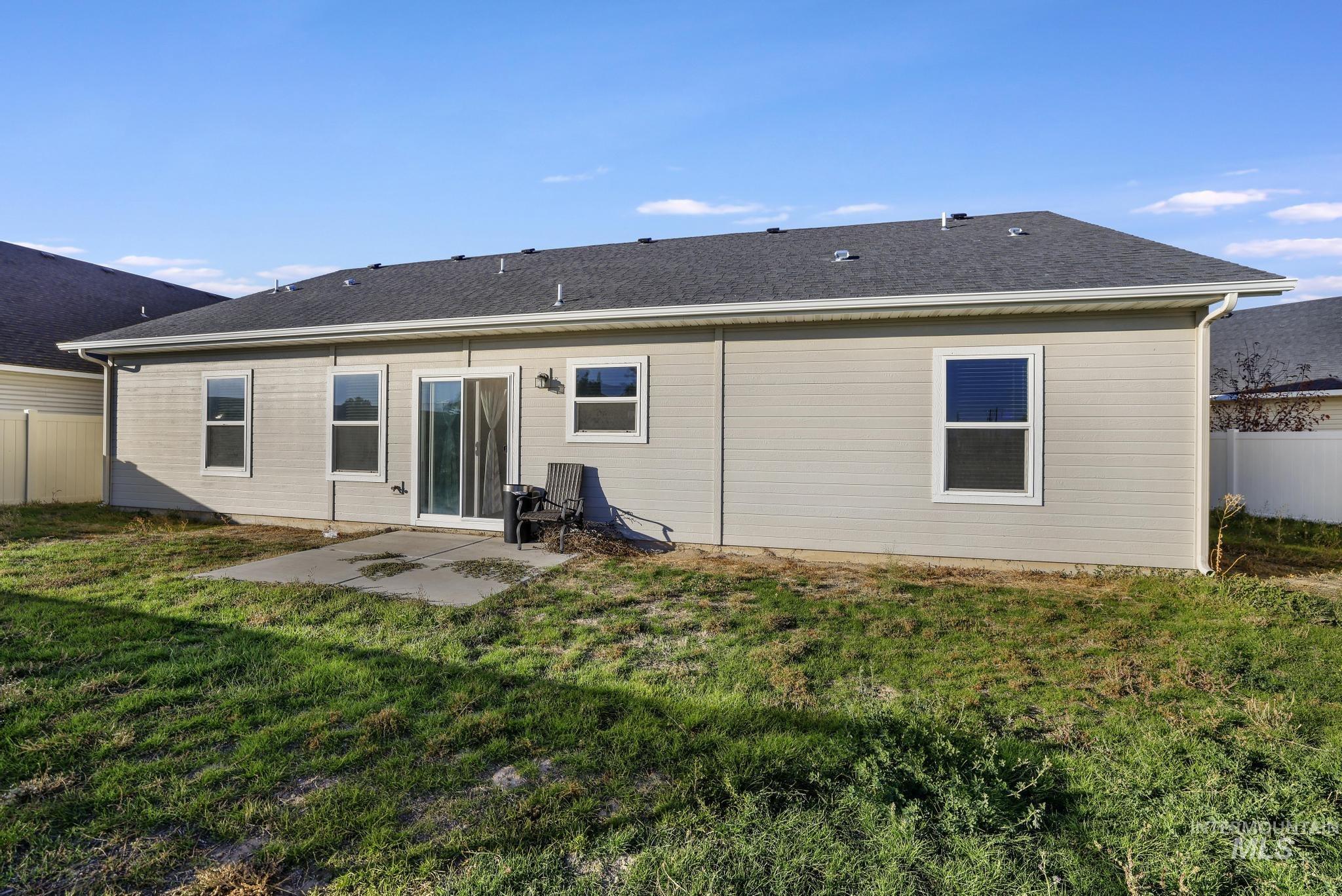 Back of property with a patio area and a shingled roof