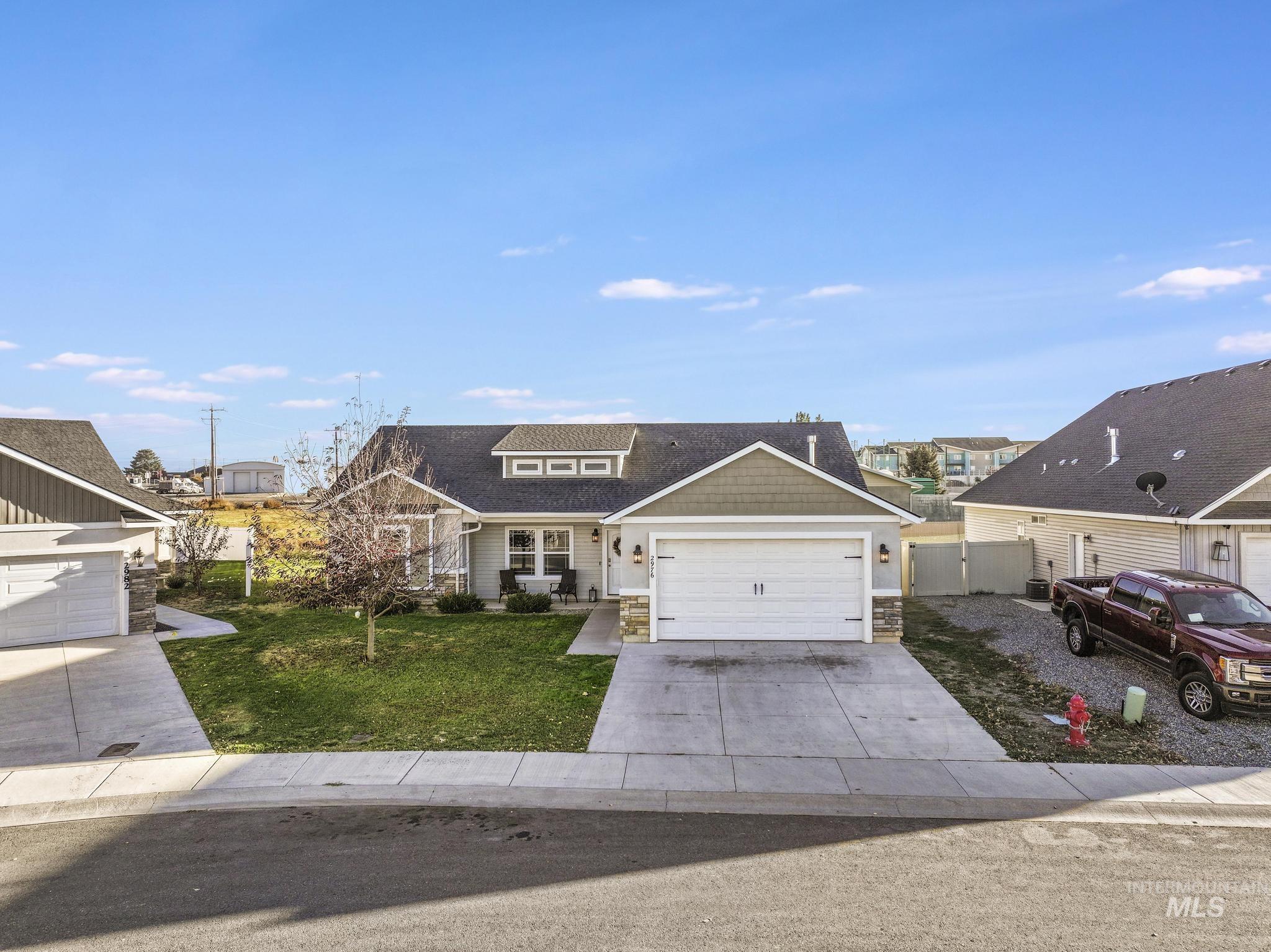 View of front facade with a front yard, driveway, stone siding, and a garage