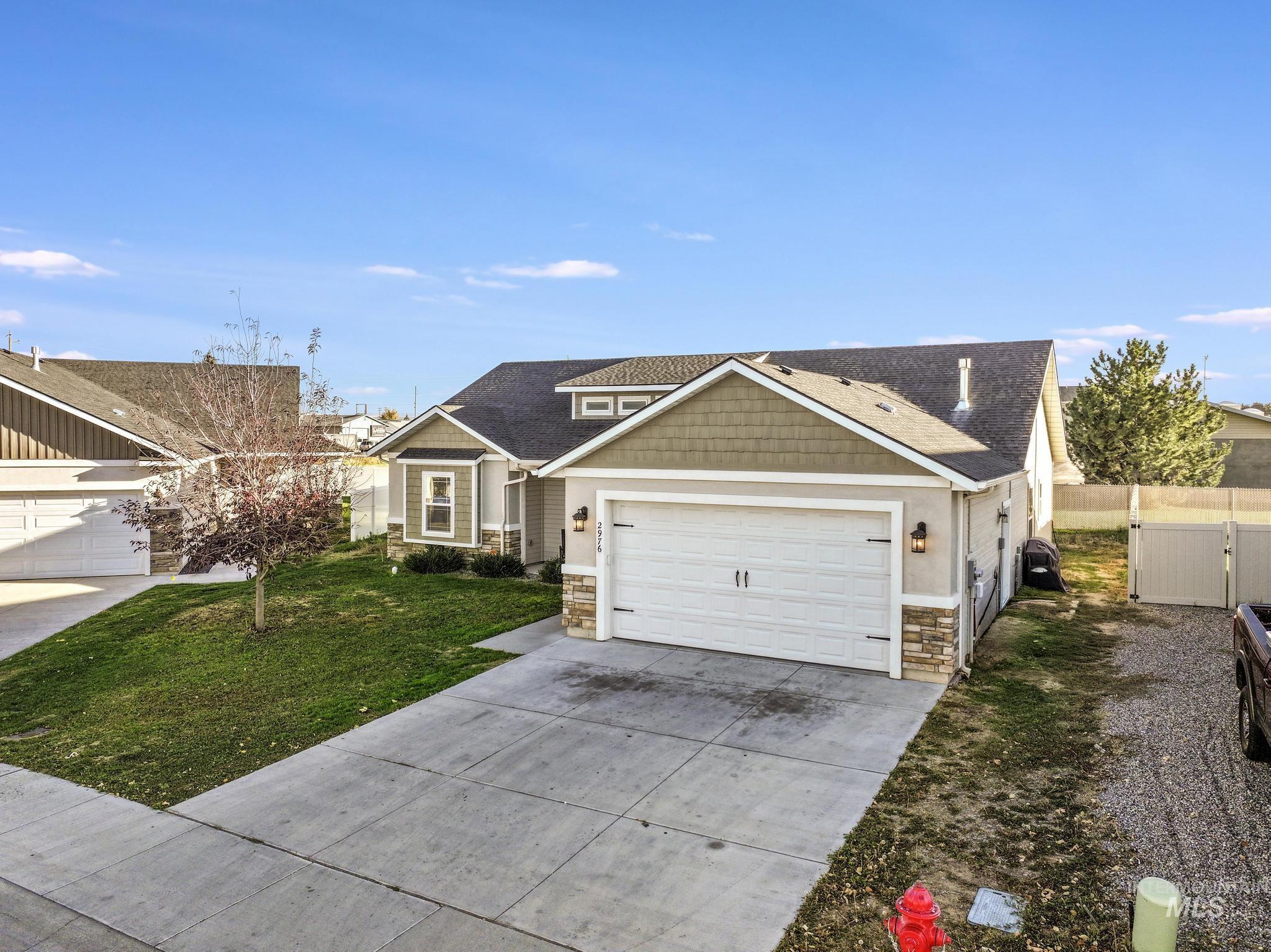 Craftsman-style home with stone siding, driveway, an attached garage, a gate, and a shingled roof