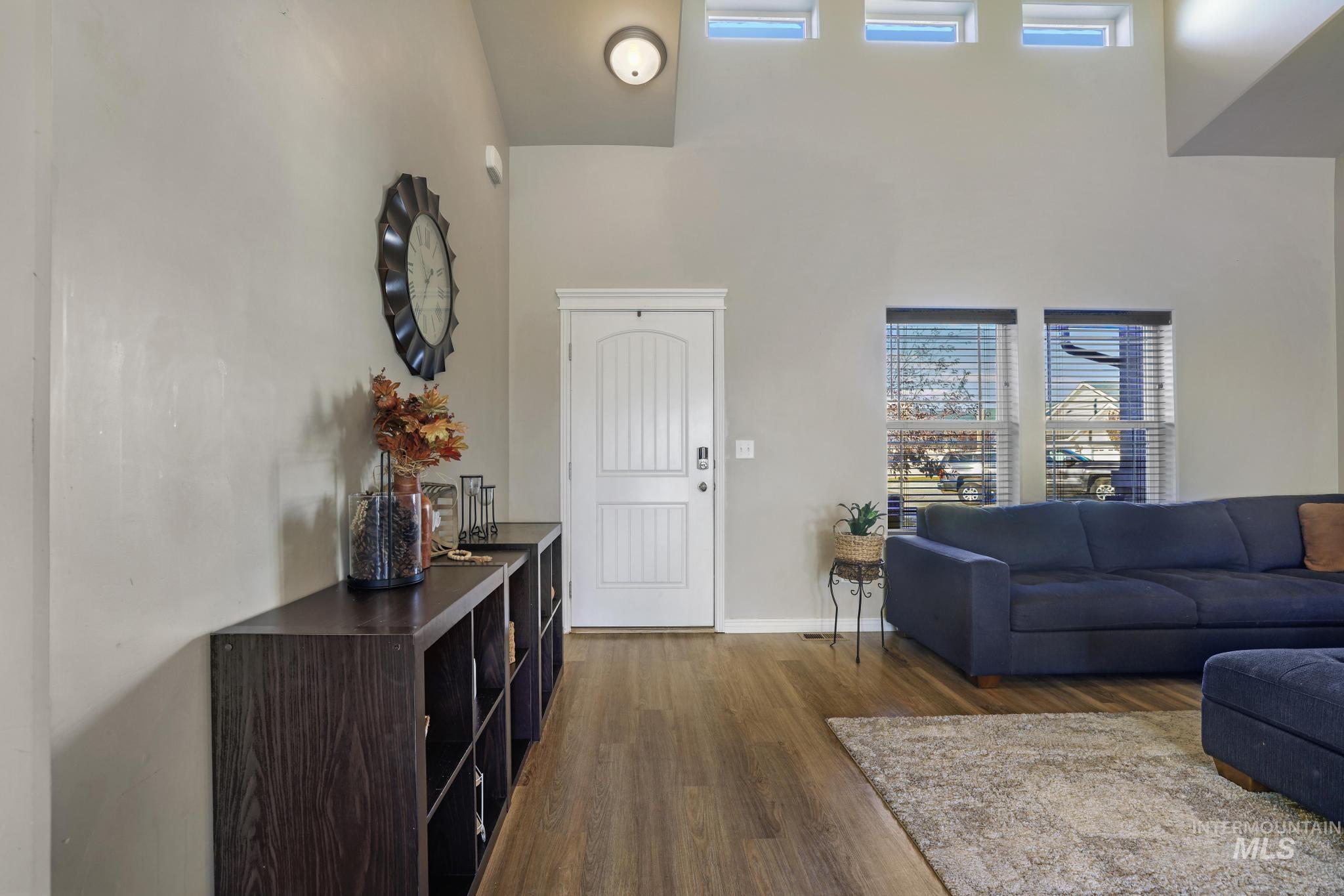 Living area with plenty of natural light, dark wood-style flooring, and a towering ceiling