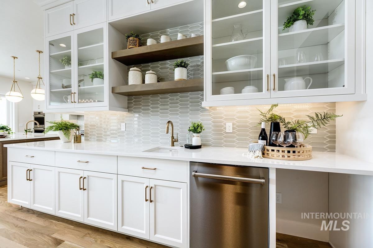 Bar area with white cabinets, appliances with stainless steel finishes, backsplash, and pendant lighting